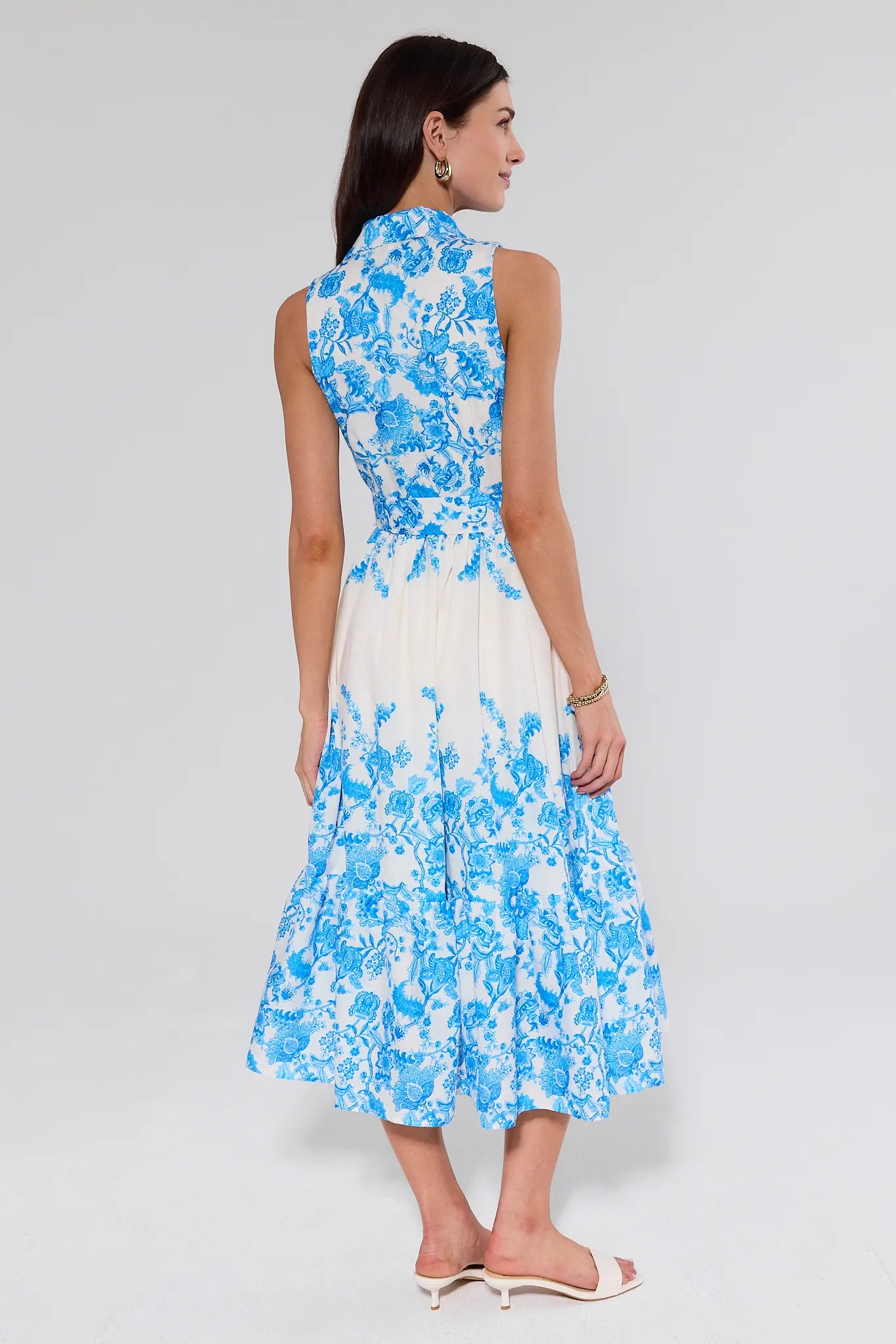 Woman wearing a blue and white floral dress on a gray background