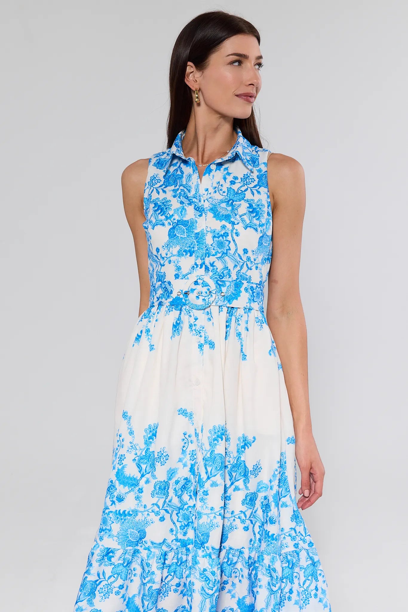 Woman wearing a sleeveless dress with blue floral pattern on a gray background