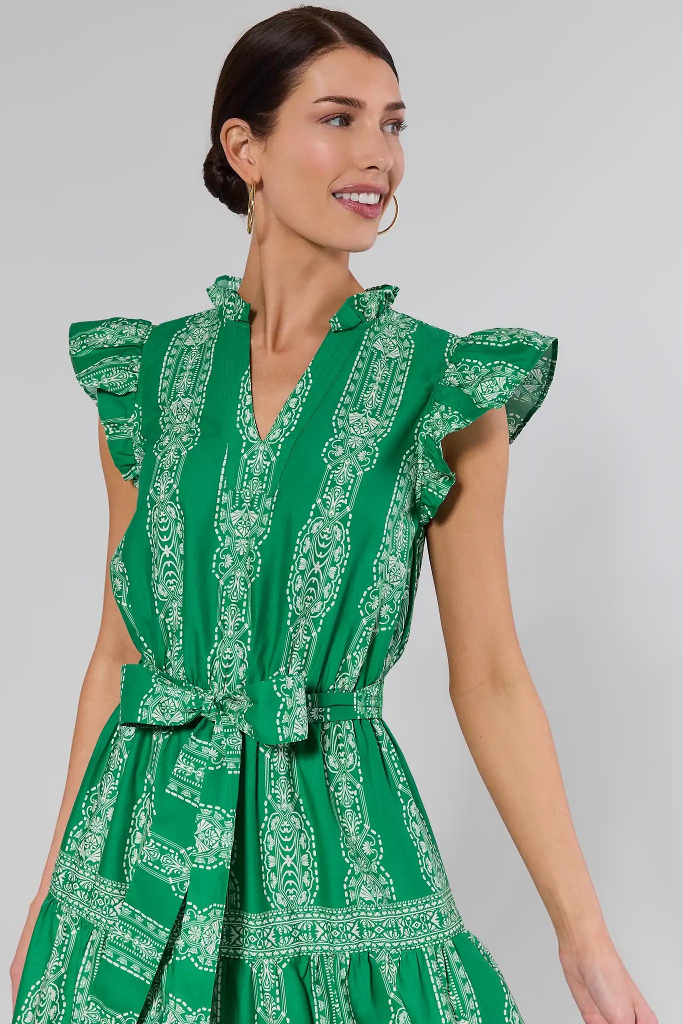 Woman wearing a green patterned dress against a plain background