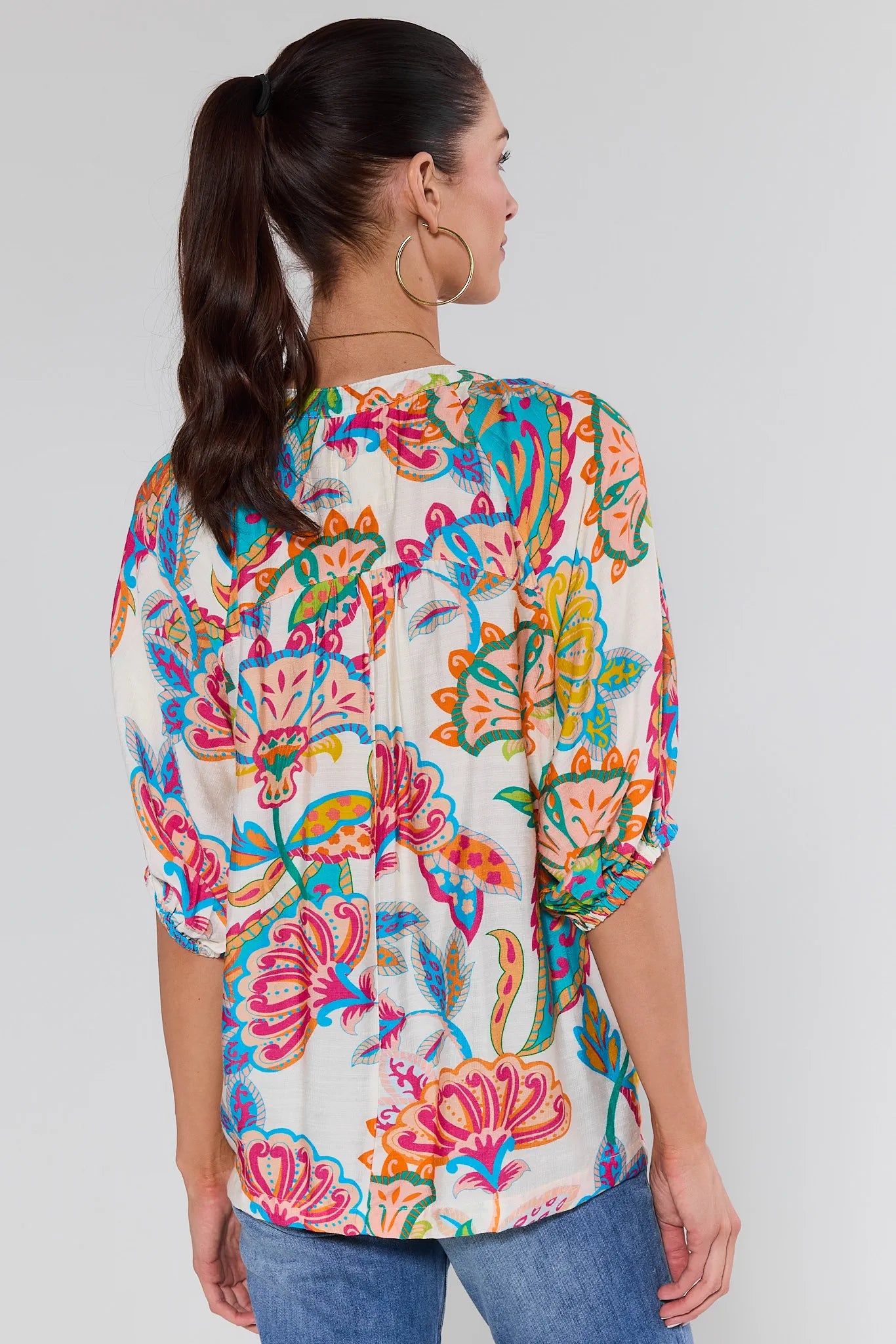 wearing a colorful floral blouse against a white background