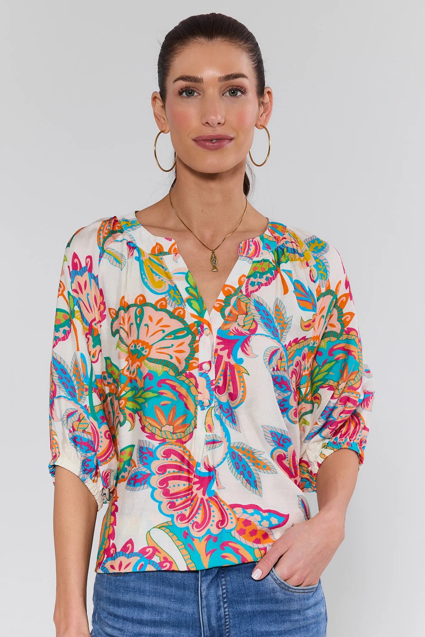 Woman wearing a colorful floral blouse against a plain background