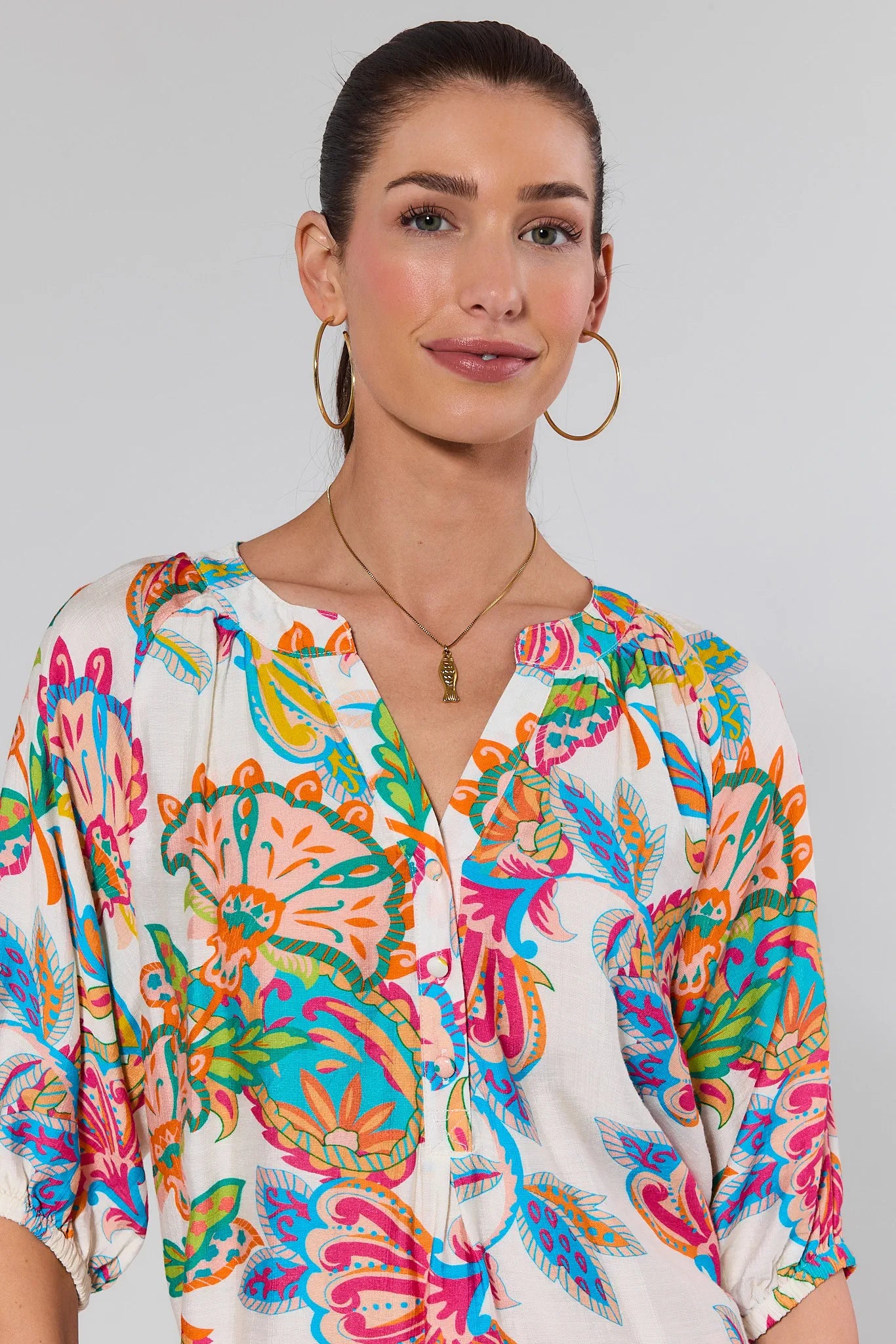 Woman wearing a colorful patterned top against a plain background