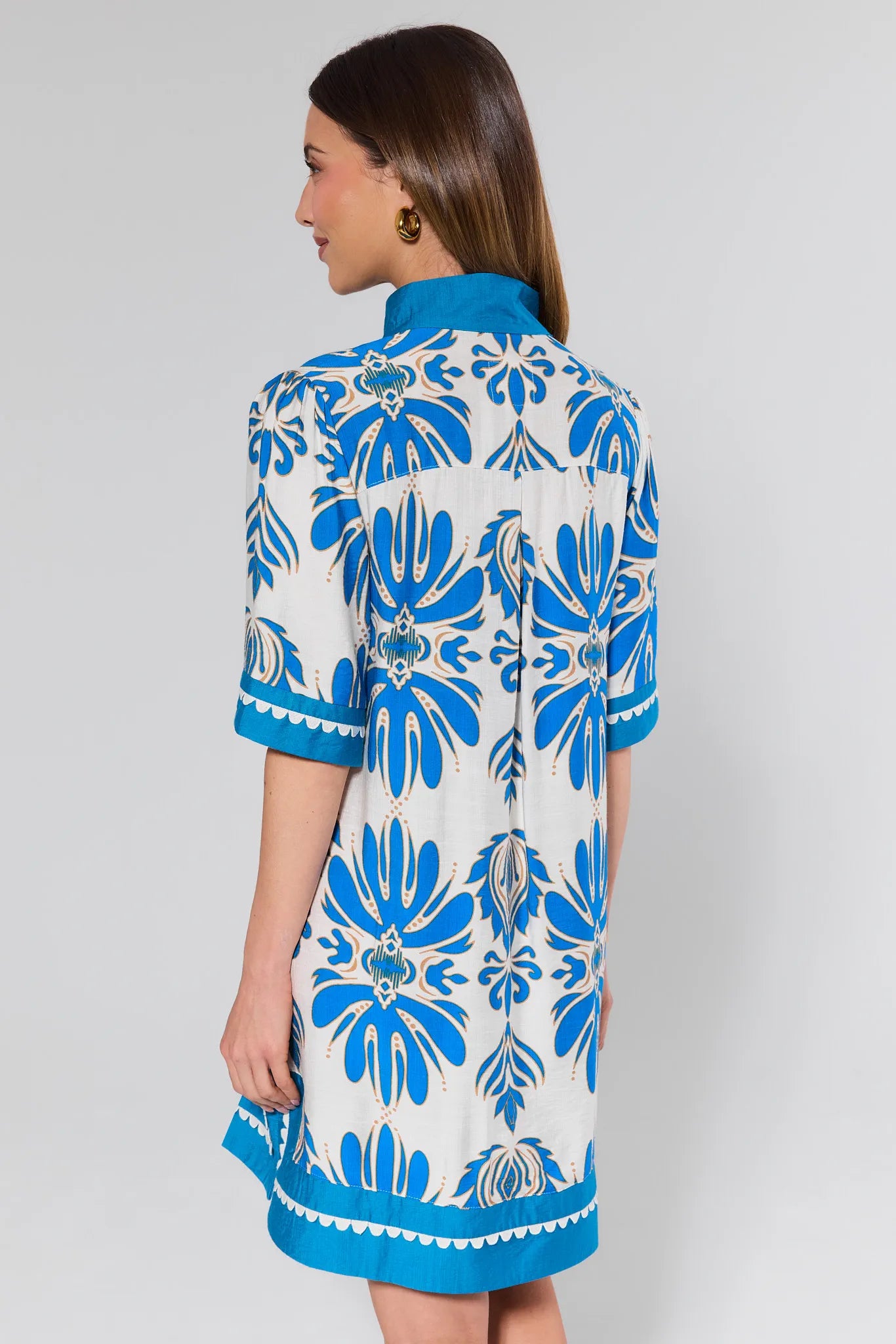 Woman wearing a blue and white patterned dress against a gray background