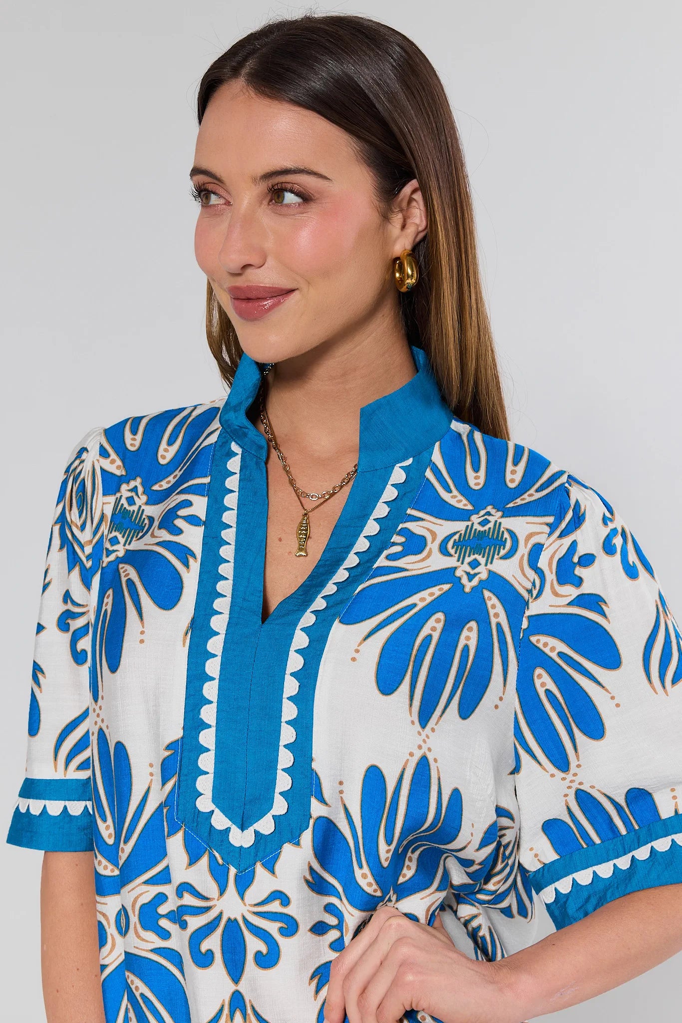 Woman wearing a blue and white patterned top against a plain background