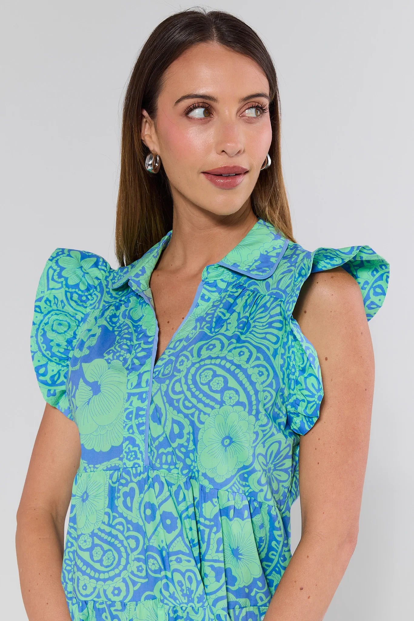 Woman wearing a green and blue patterned dress against a plain background