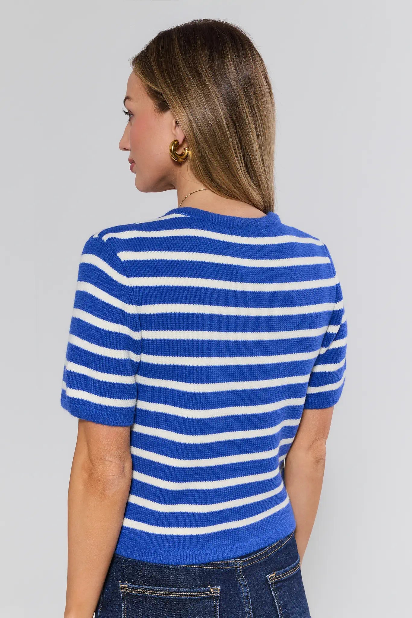 Woman wearing a blue and white striped shirt against a plain background