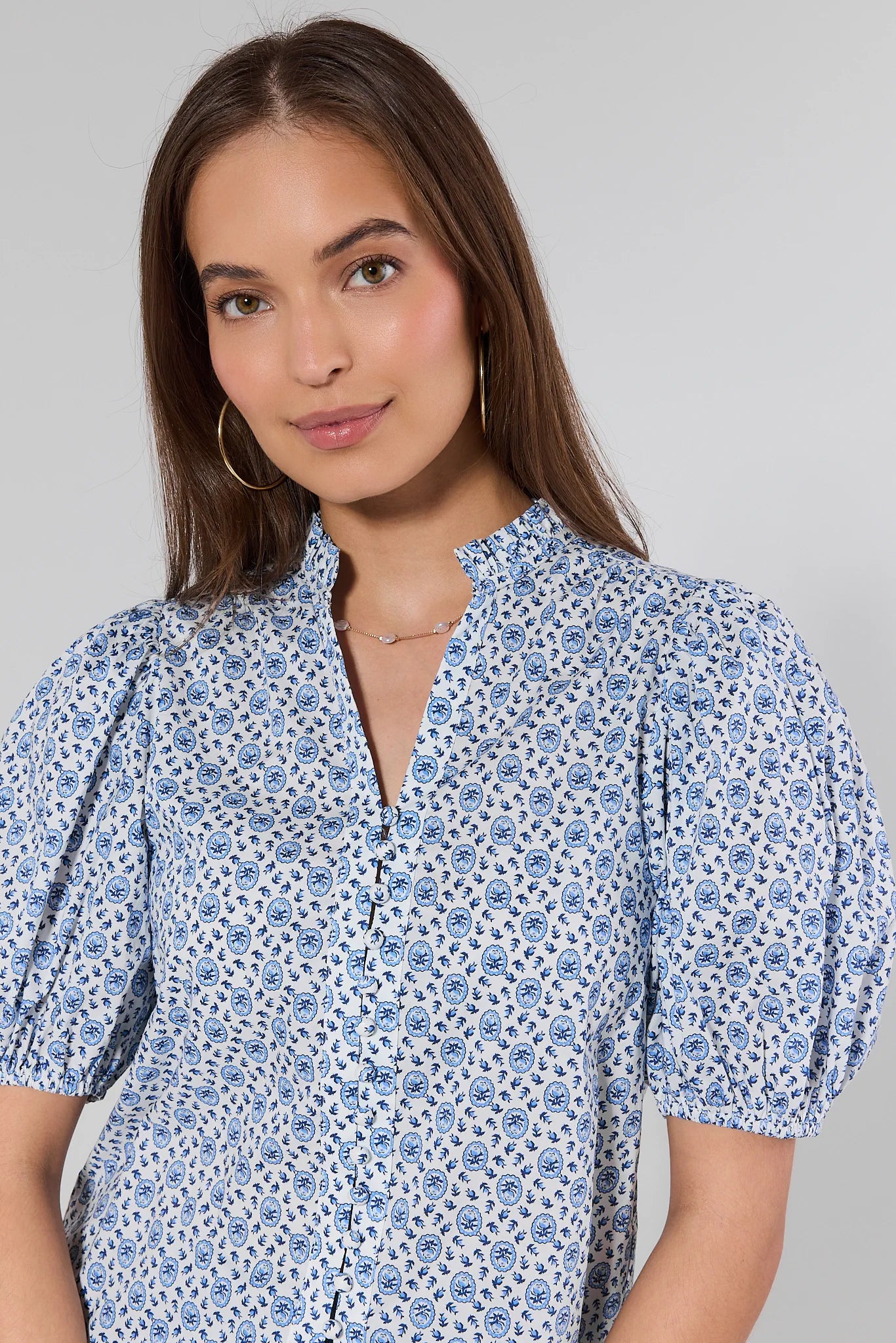 Woman wearing a blue floral dress against a gray background