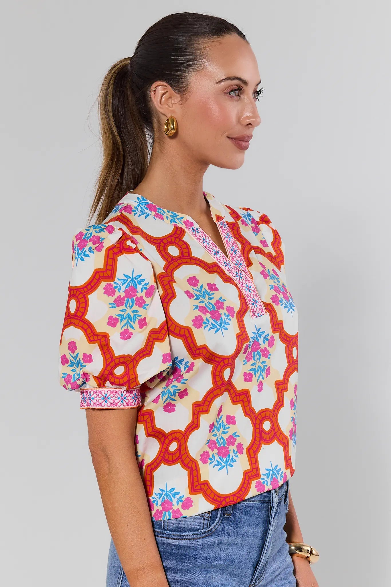 Woman wearing a colorful patterned top with a plain background