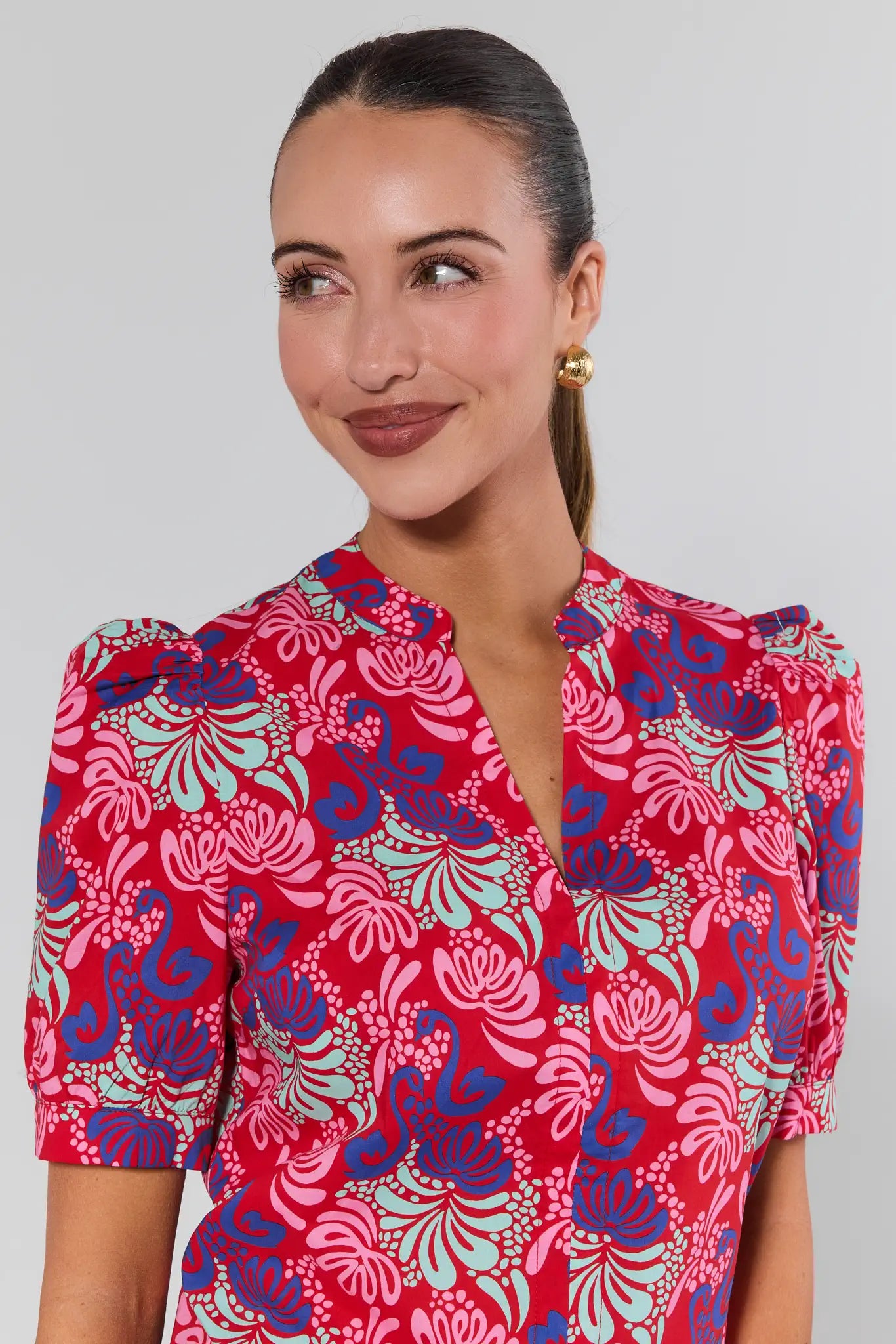 Woman wearing a red floral patterned dress against a gray background