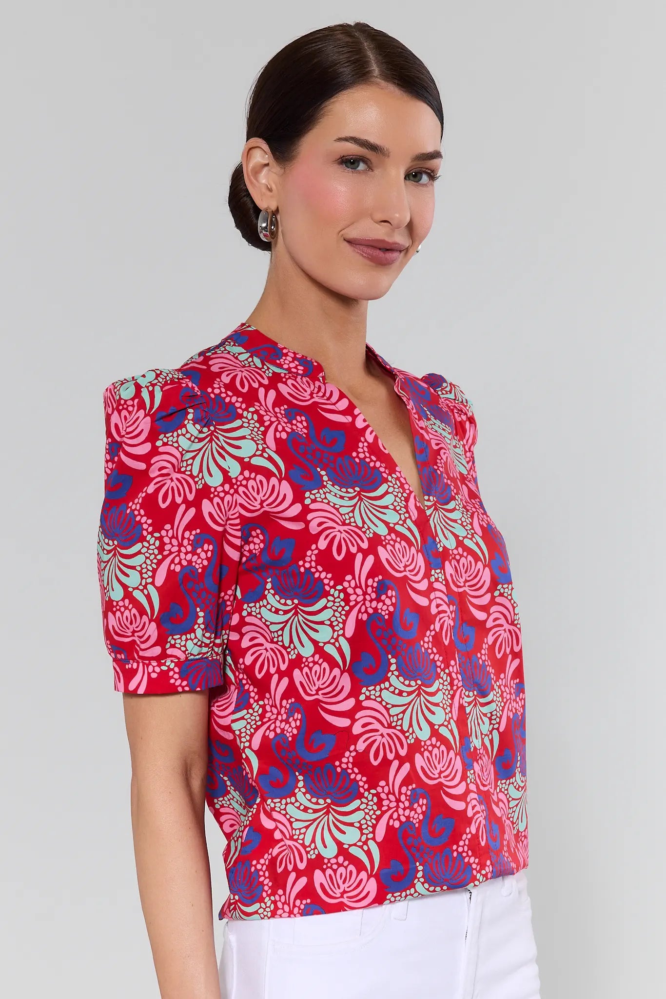 Woman wearing a colorful floral blouse against a plain background