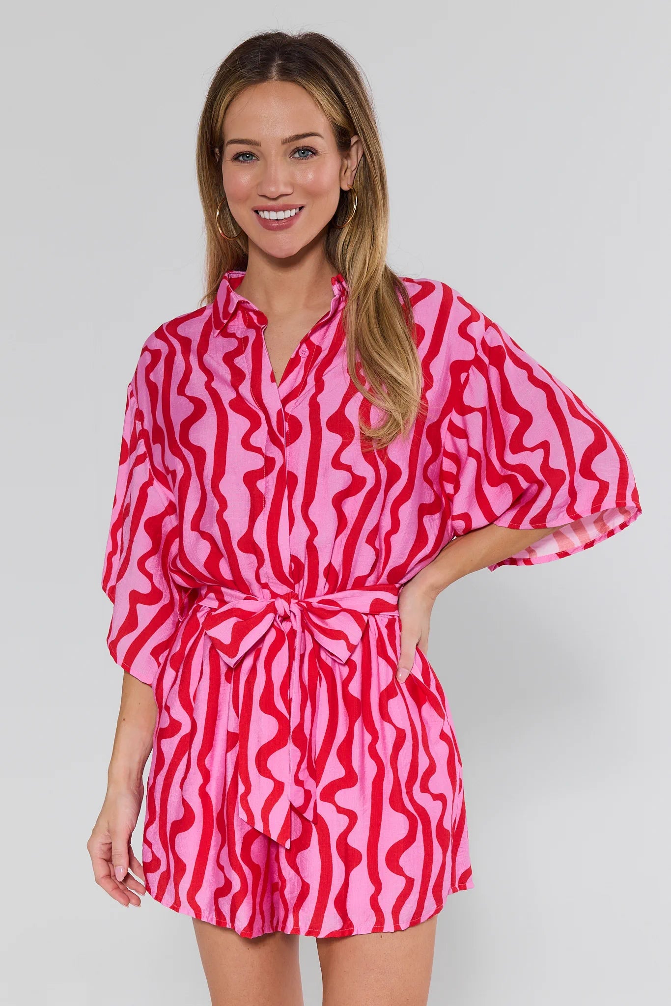 Woman wearing a pink and red patterned dress against a white background