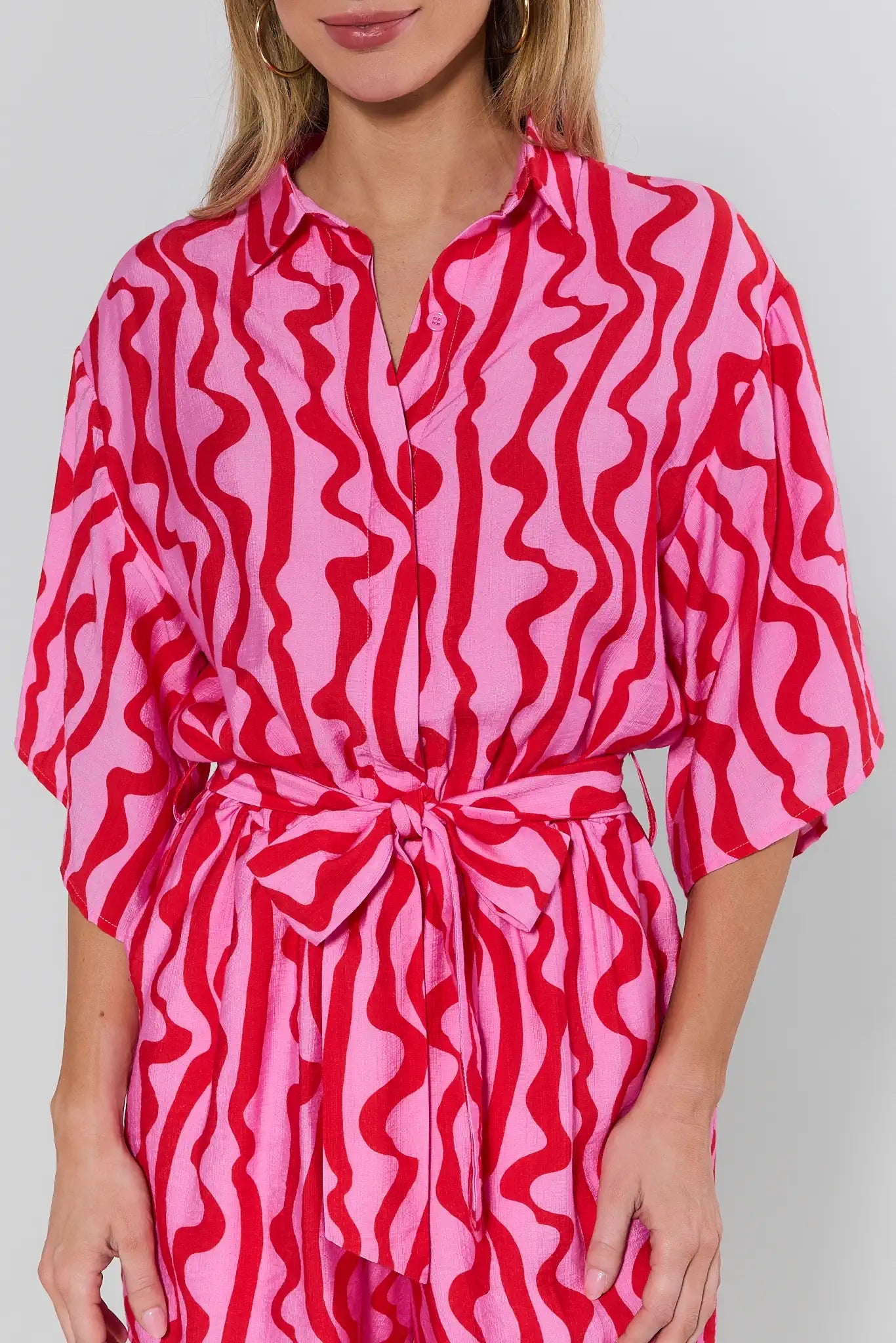 Person wearing a pink and red patterned outfit on a plain background