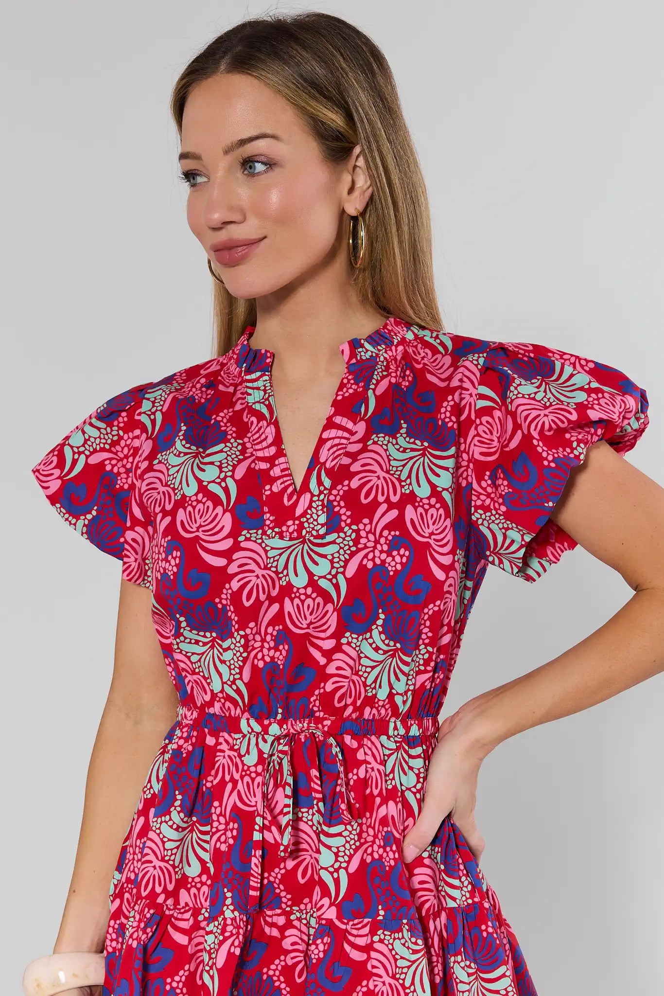 Woman wearing a red floral dress against a plain background