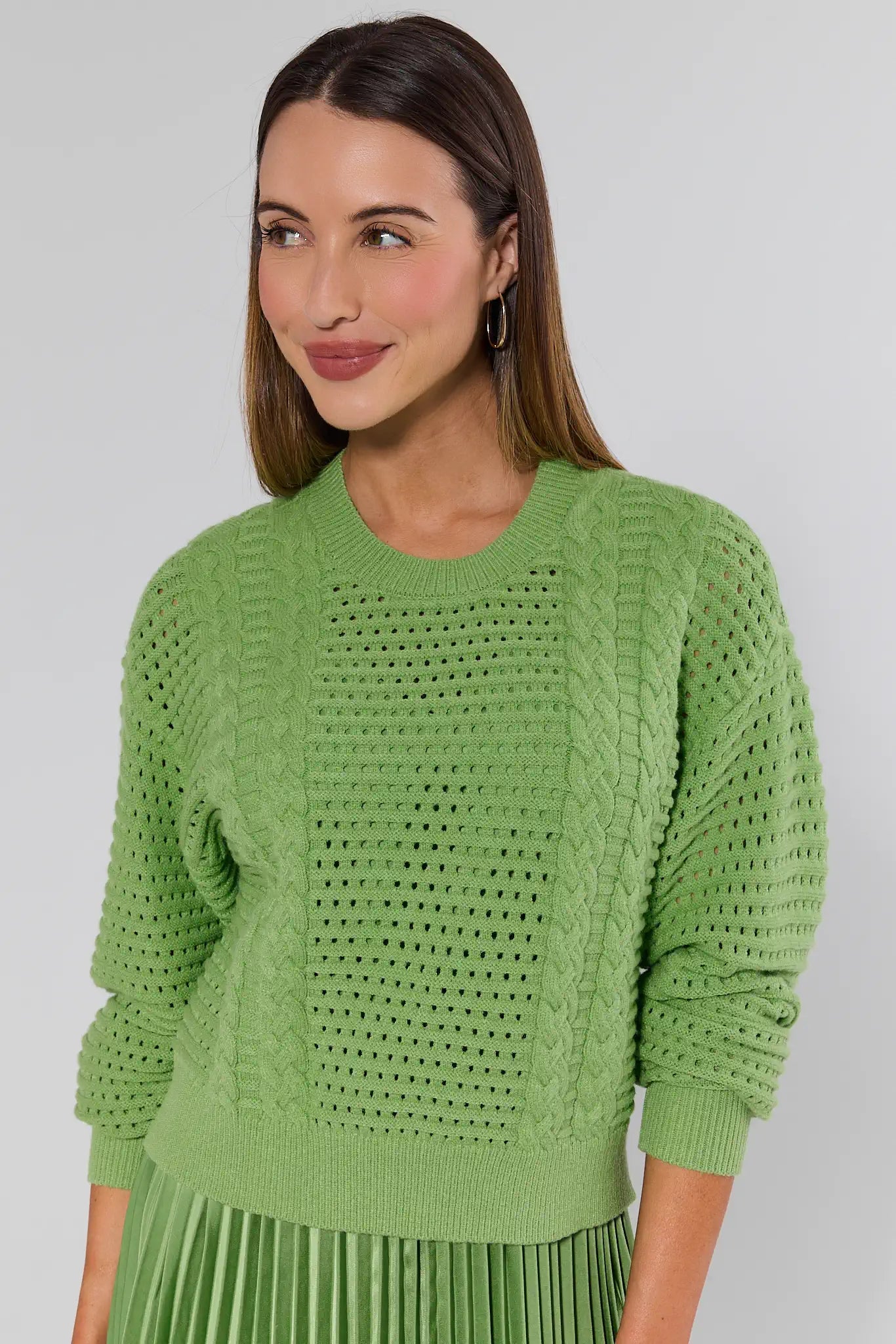 Woman wearing a green knitted sweater against a plain background
