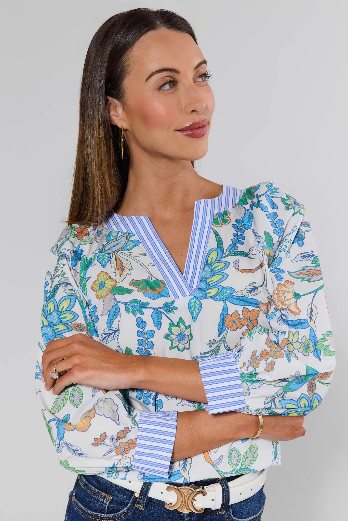 Woman wearing a colorful floral blouse with a striped collar against a gray background