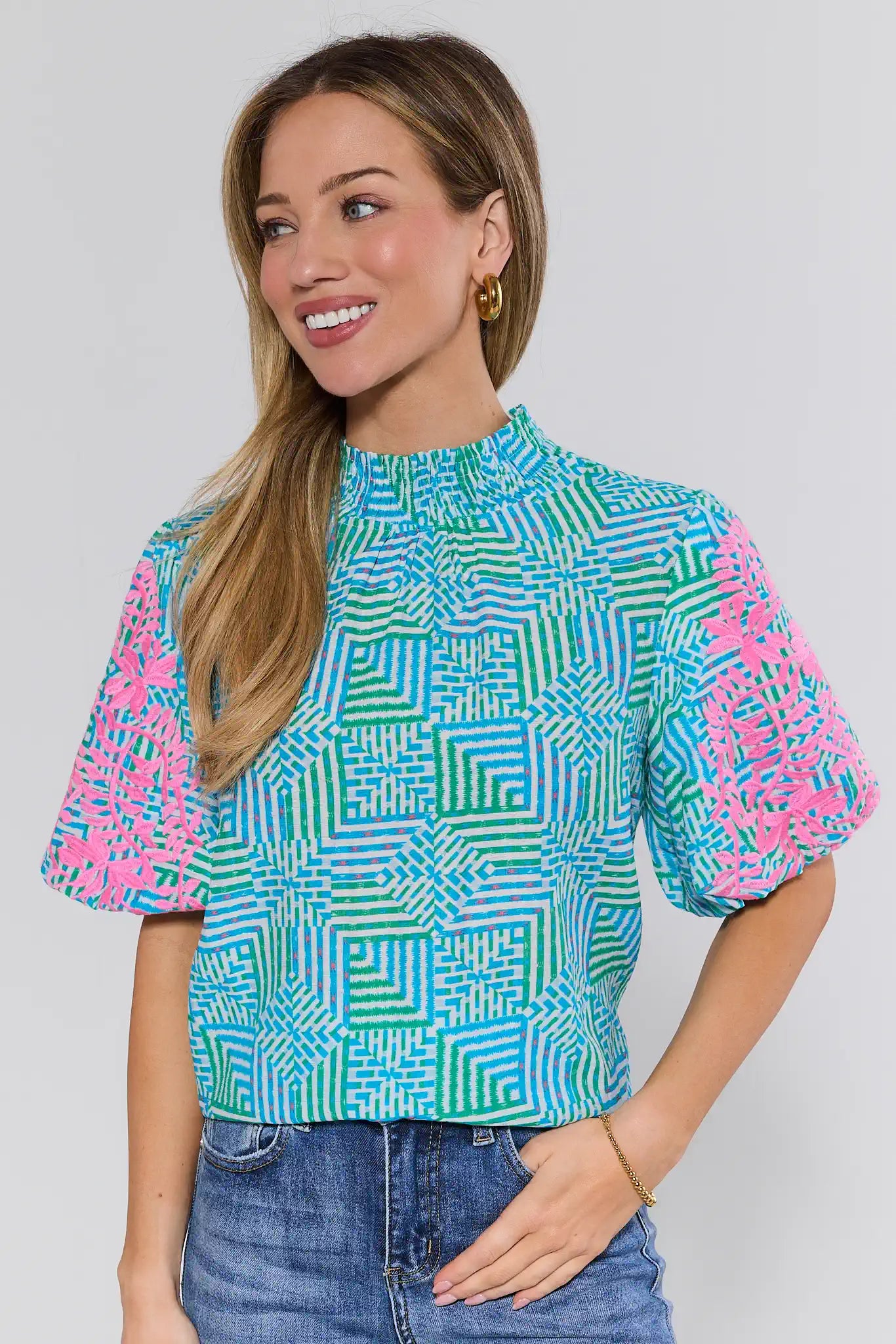 Woman wearing a colorful geometric patterned top against a plain background