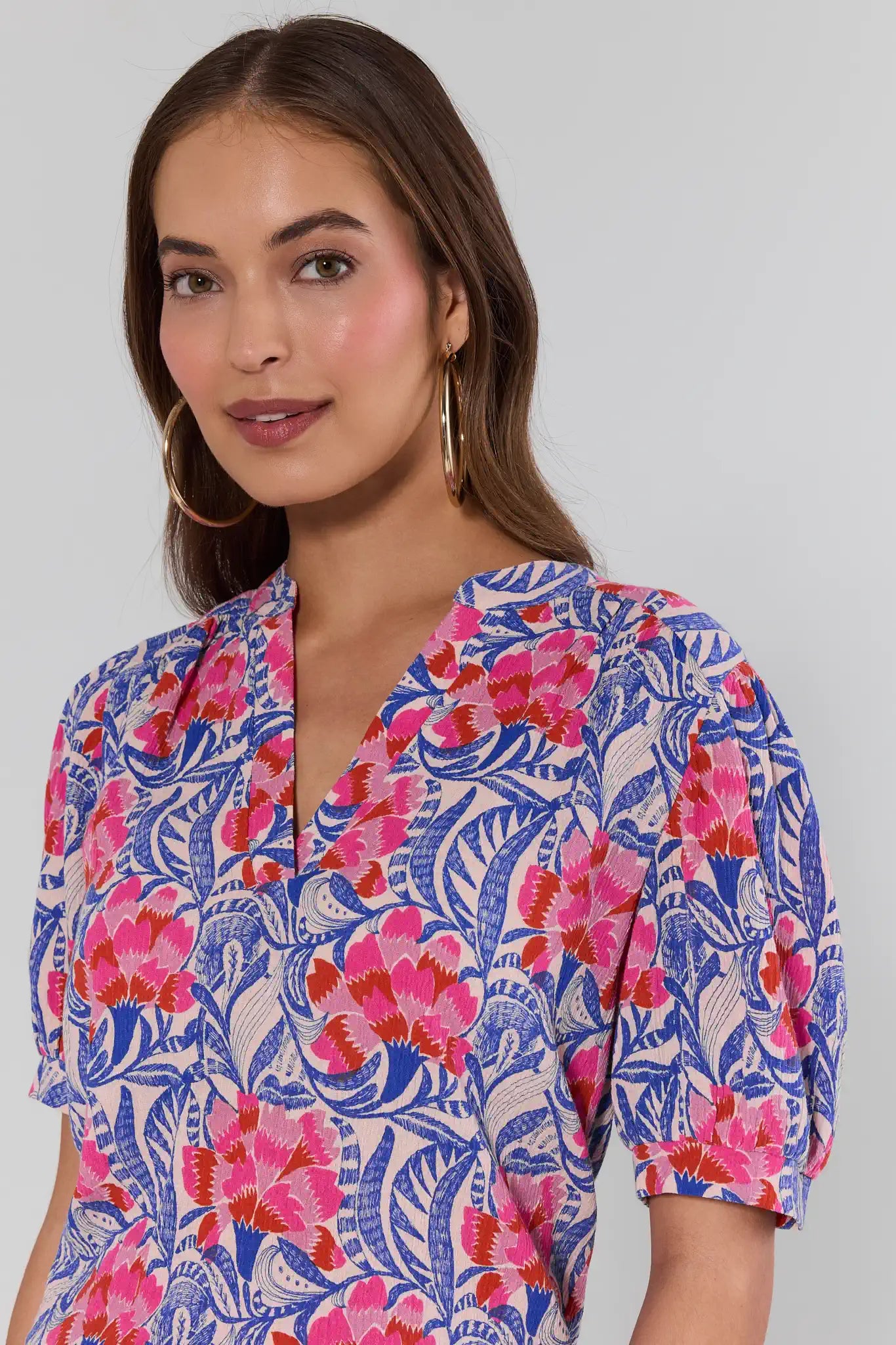 Woman wearing a colorful floral dress against a plain background