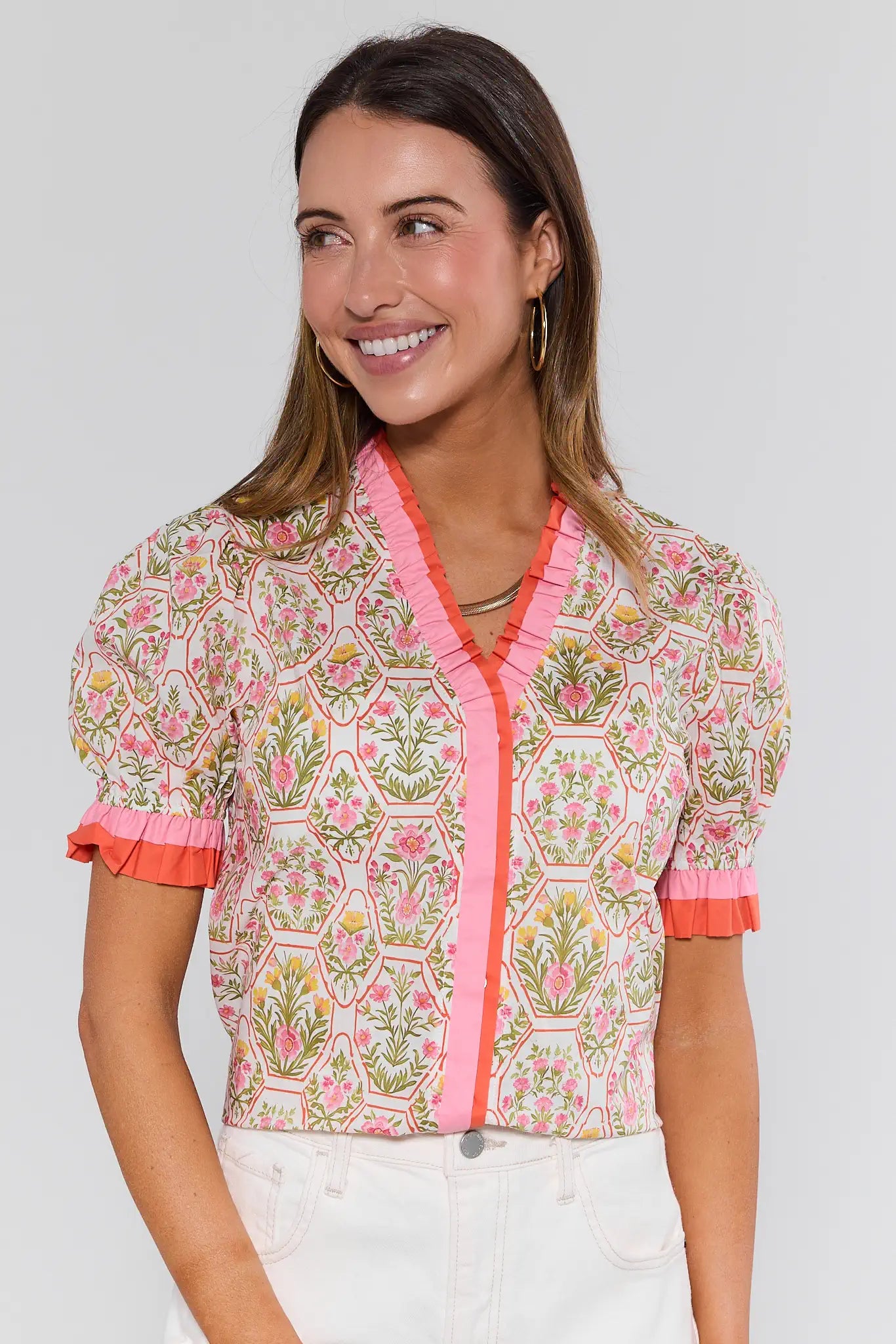 Woman wearing a floral blouse with pink accents on a plain background