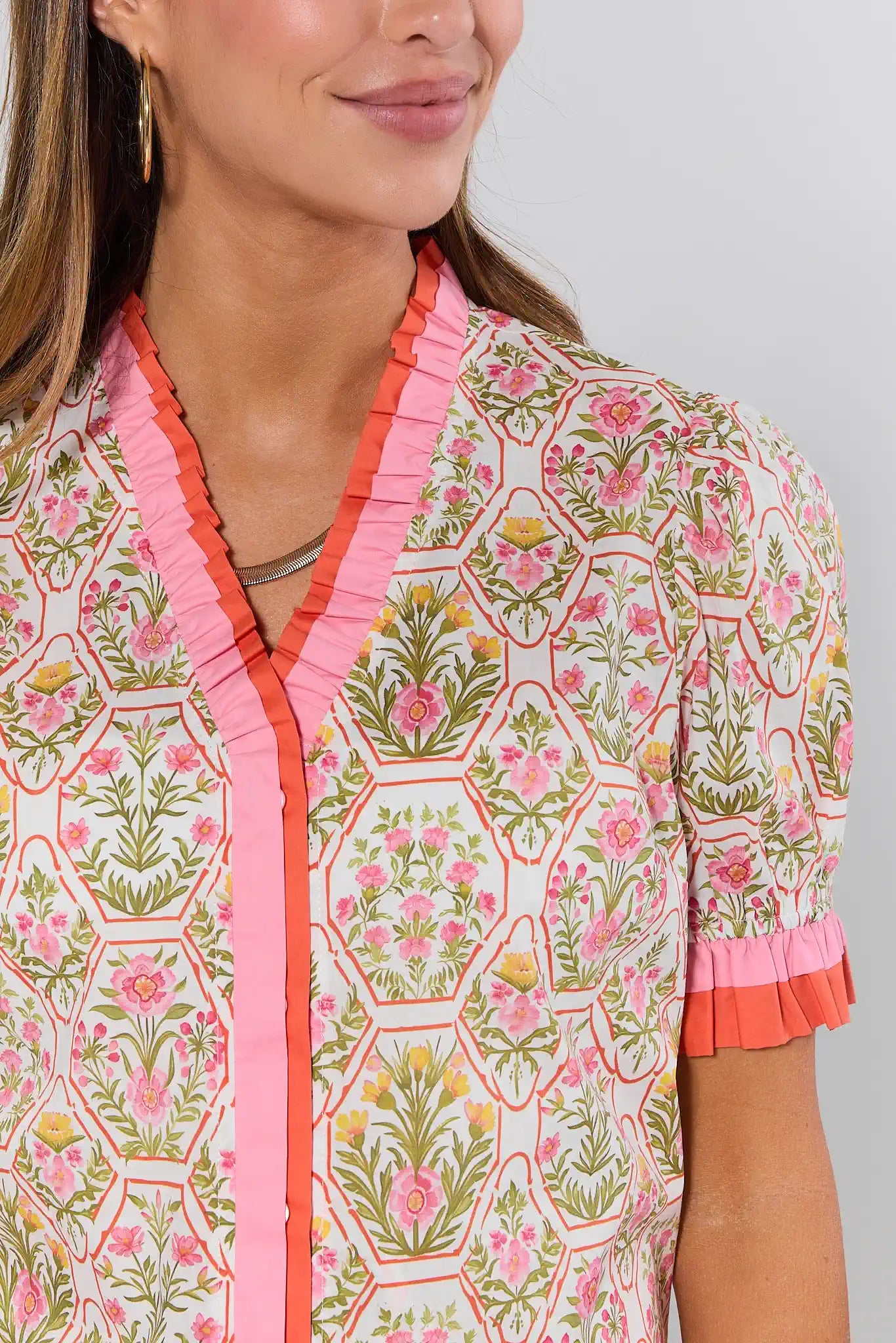 Woman wearing a floral blouse with pink accents on a gray background