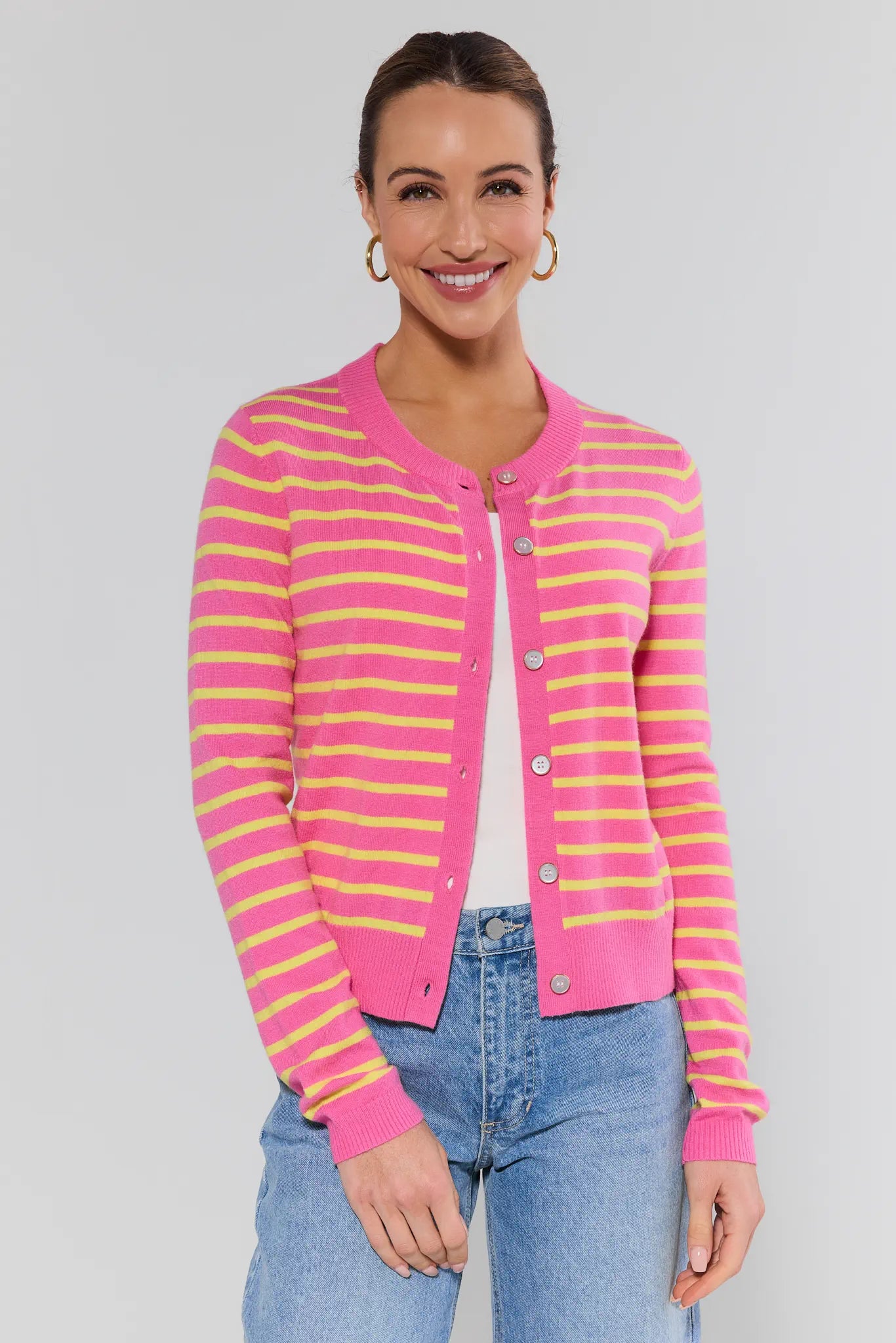 Woman wearing a pink and yellow striped cardigan on a plain background