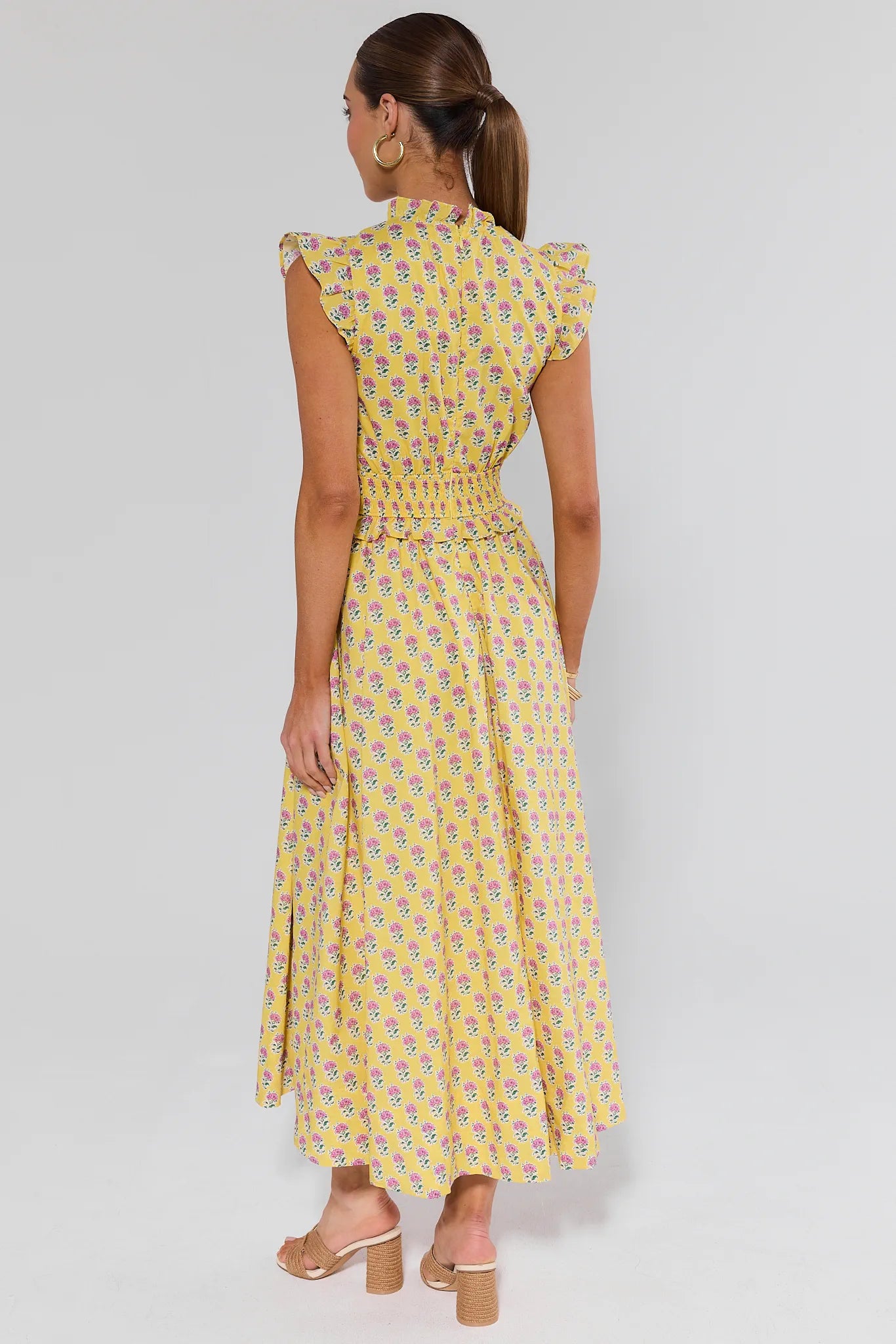 Woman wearing a yellow patterned dress on a plain background