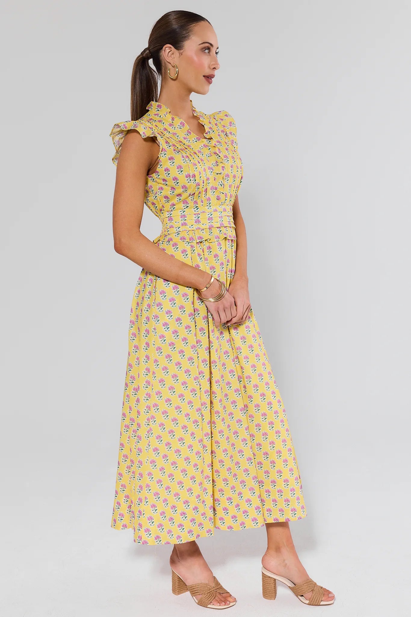 Woman wearing a yellow floral dress on a gray background