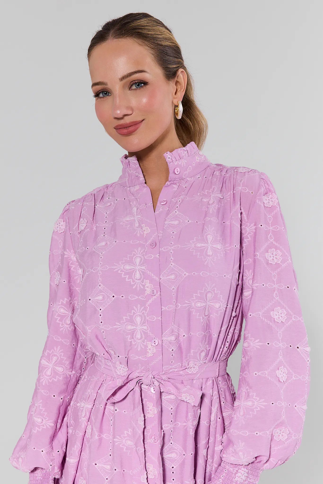 Woman wearing a pink dress with a subtle pattern on a plain background