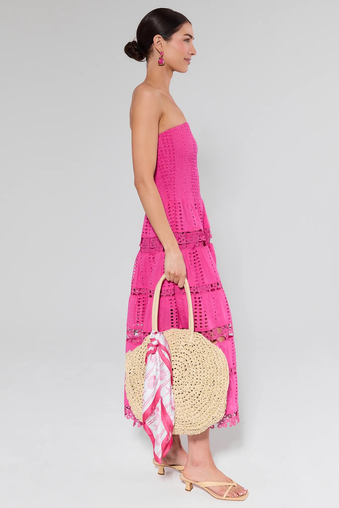 Woman wearing pink dress holding bag on plain background