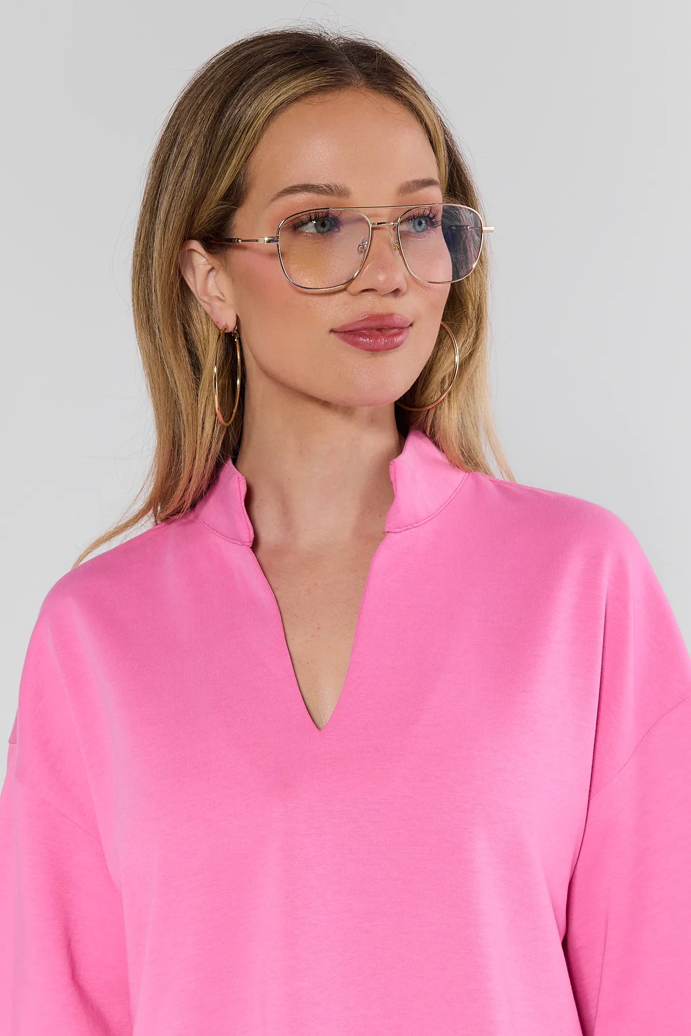 woman wearing glasses with pink sweater on white background