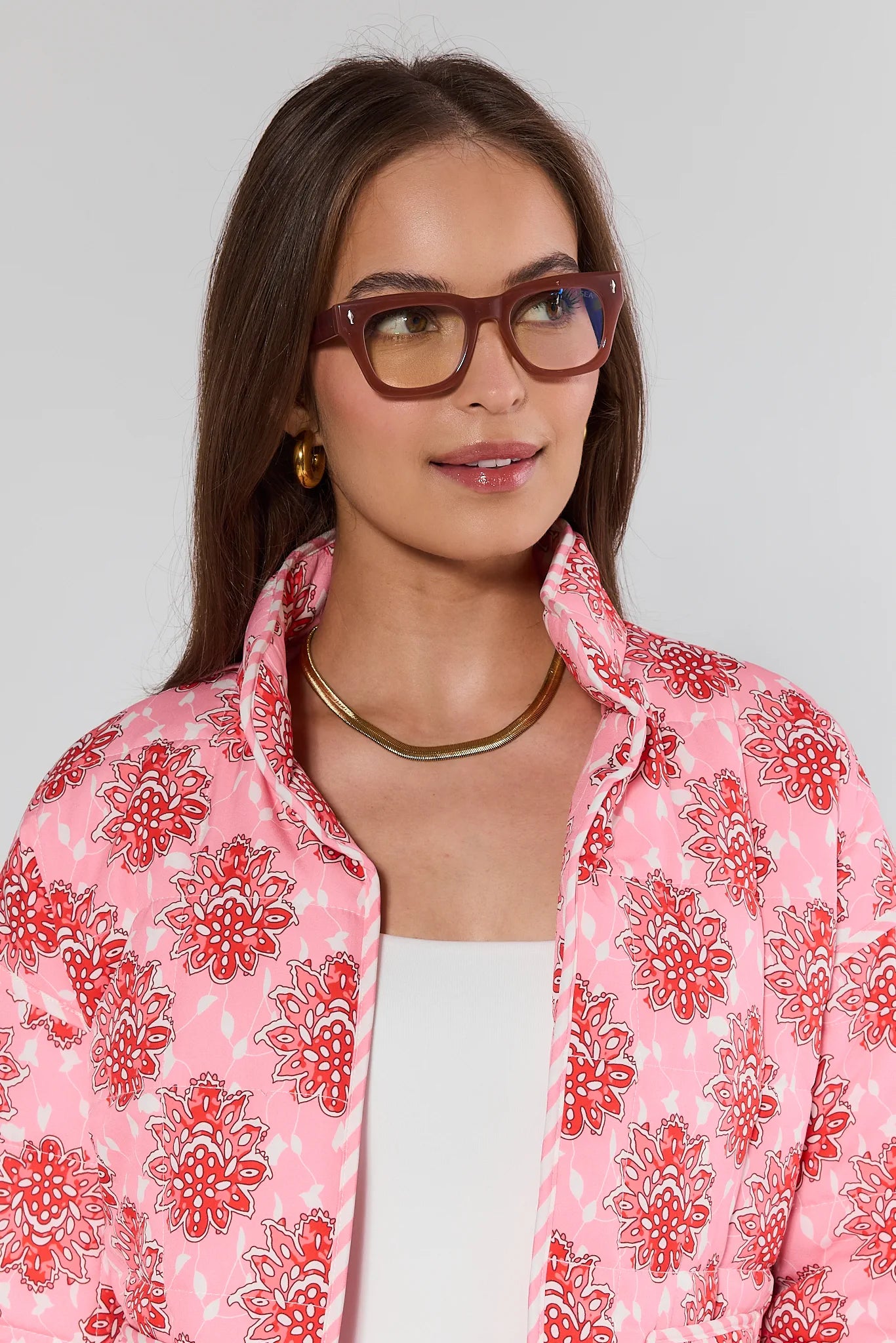 woman wearing brown glasses and pink jacket on white background