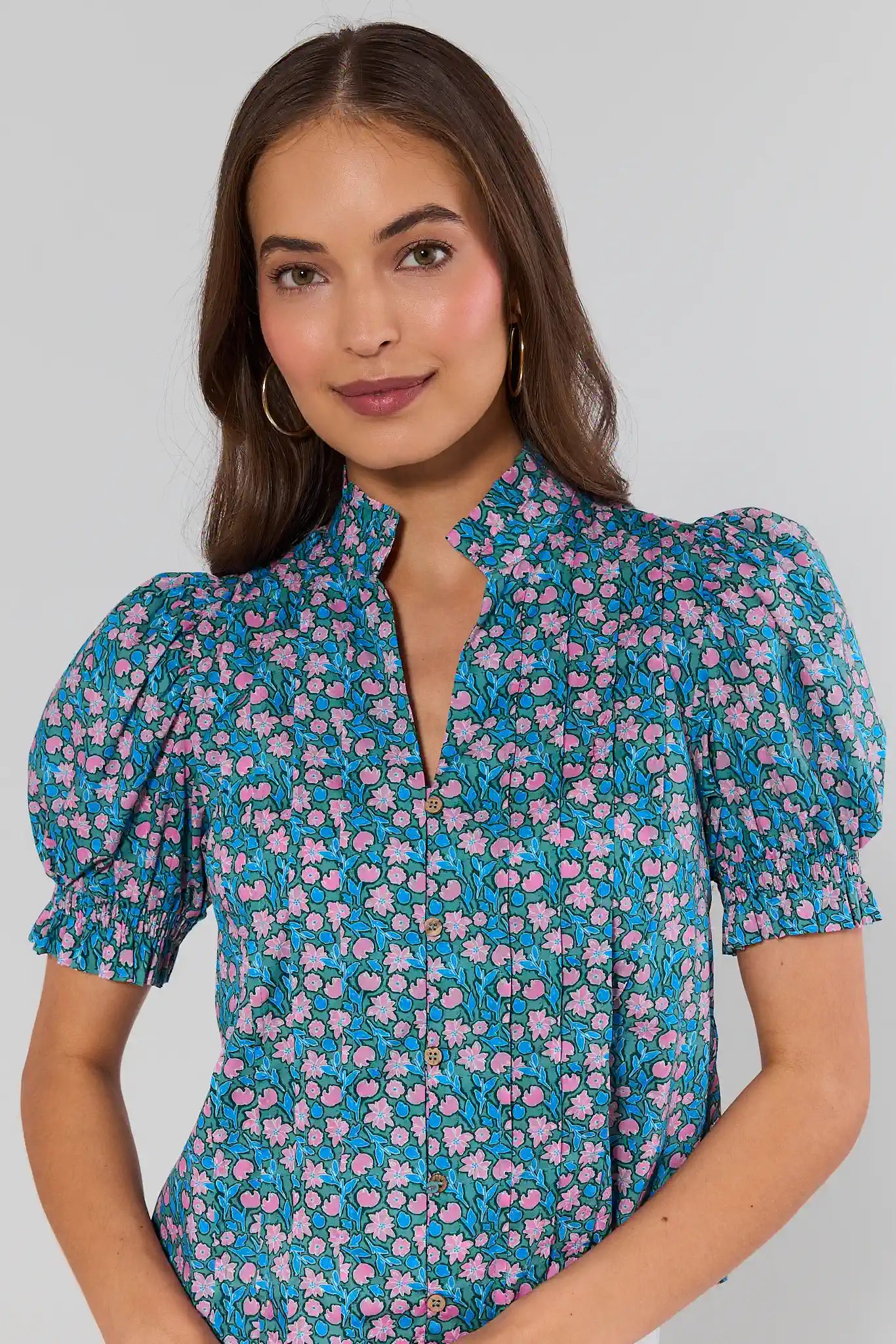 Woman wearing a floral blouse with puff sleeves against a gray background