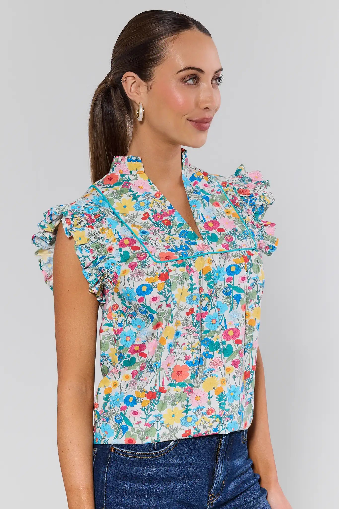 Woman wearing a colorful floral blouse against a plain background