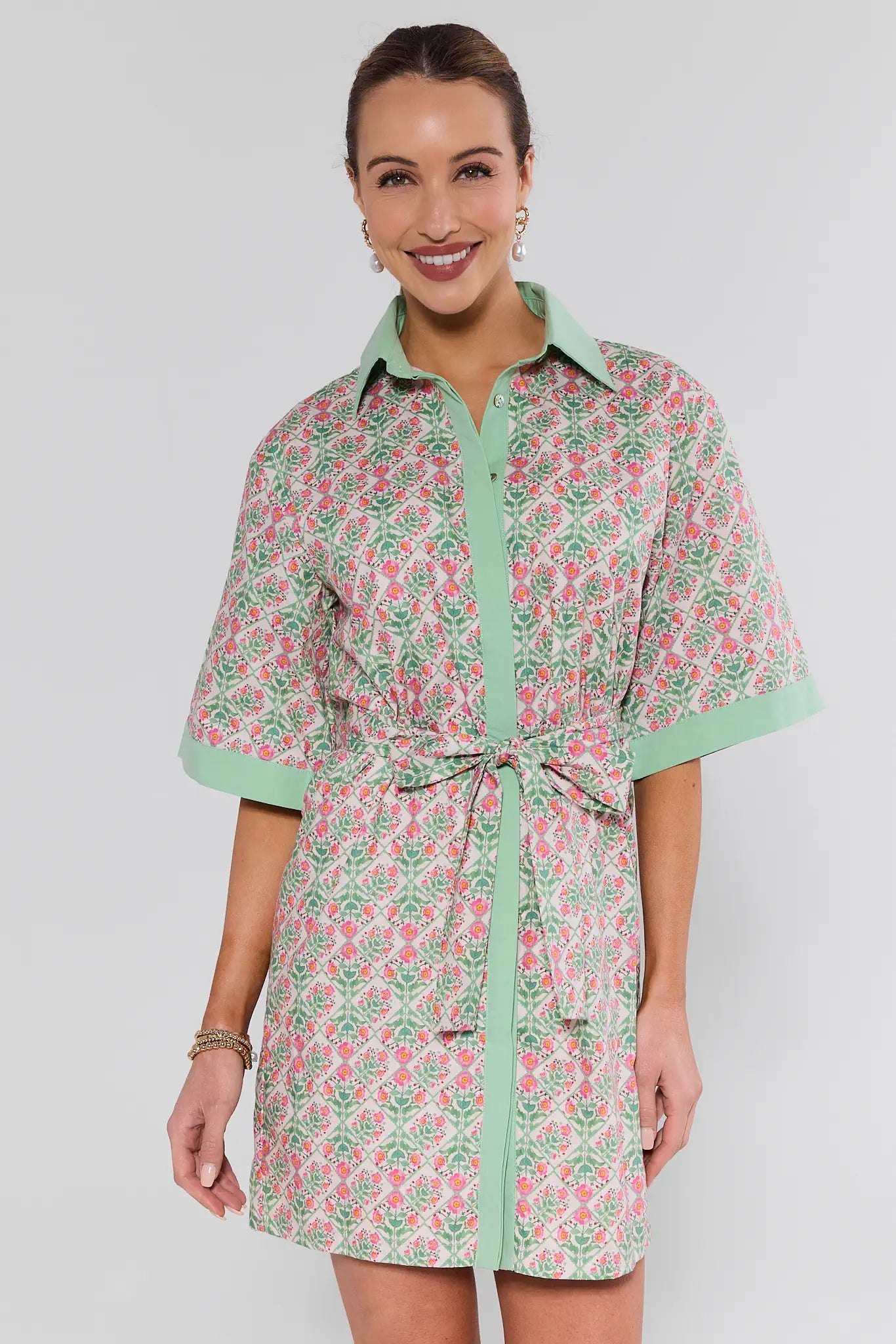 Woman wearing a floral dress with green accents on a plain background