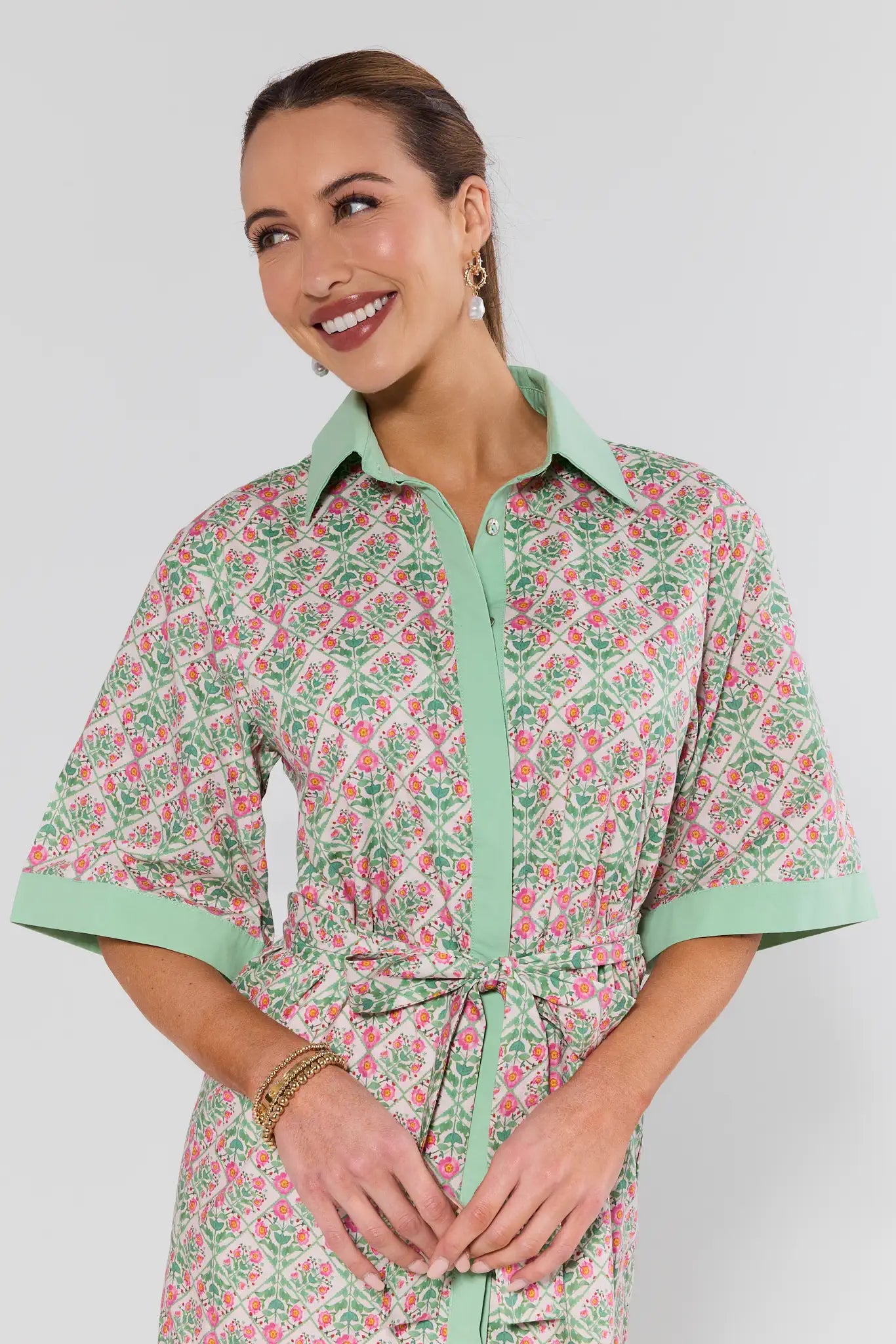 Woman wearing a floral dress with green accents on a white background