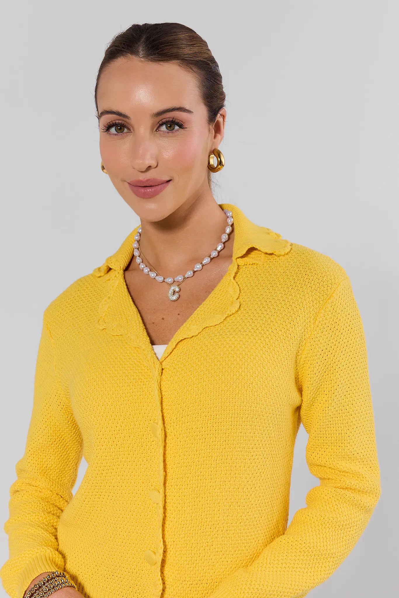Woman wearing a yellow cardigan with a plain background