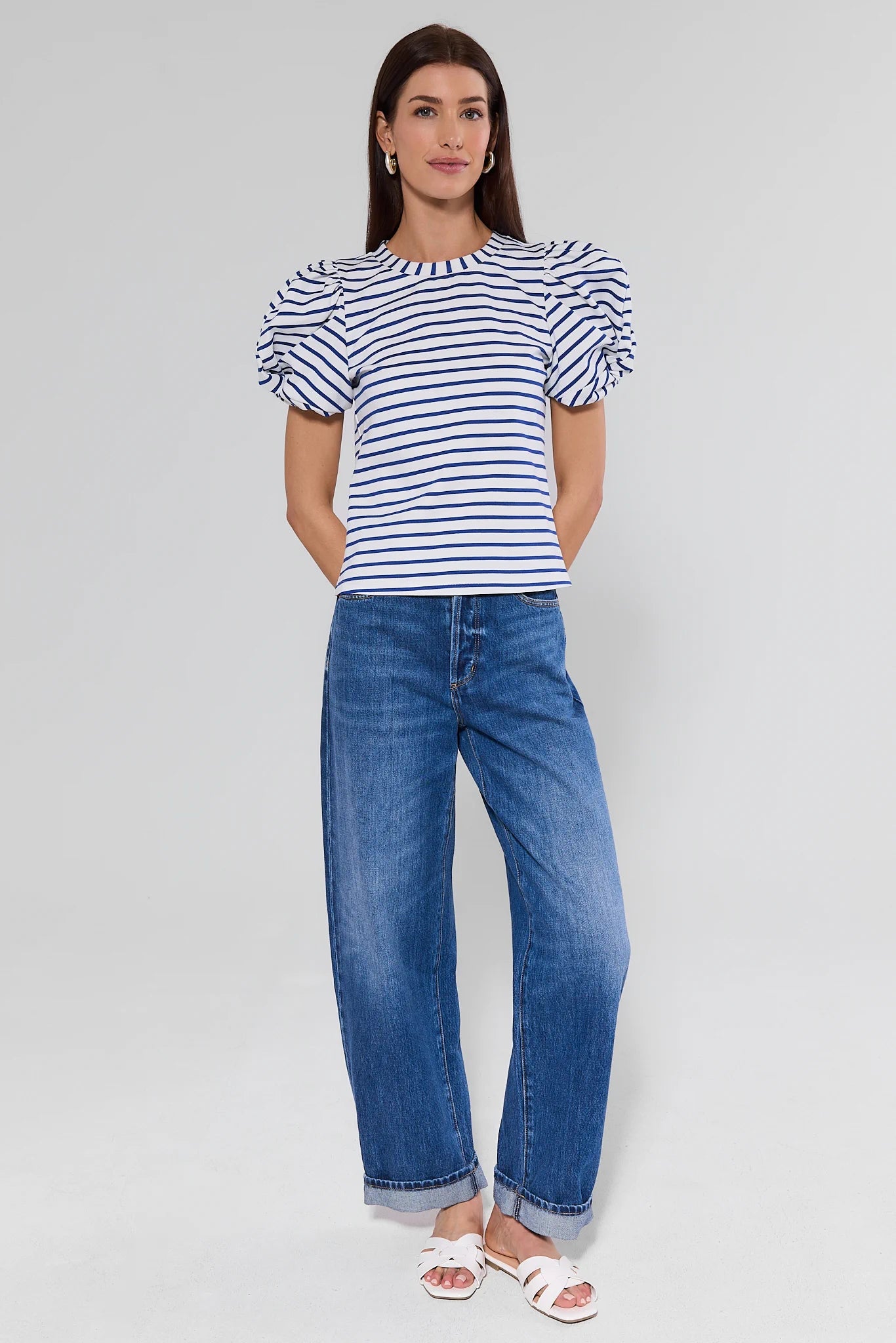 Woman wearing a striped shirt and blue jeans on a white background