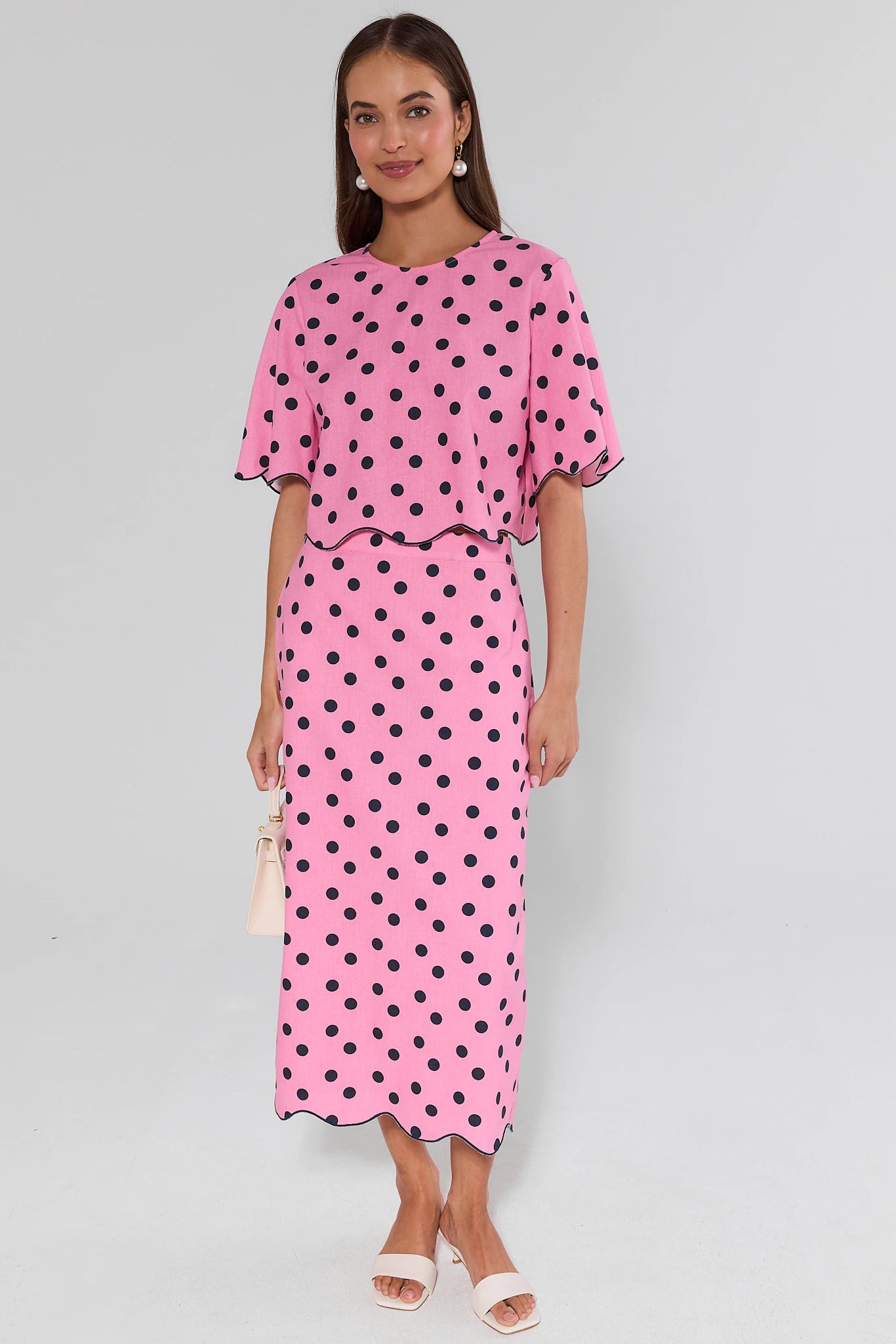 Woman wearing a pink polka dot dress on a gray background