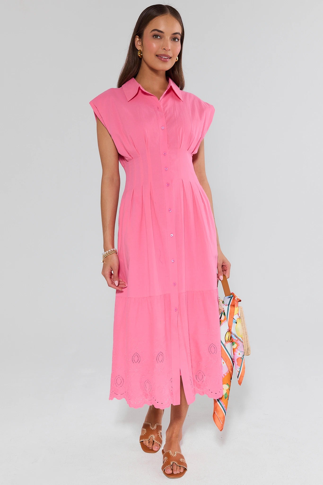 Woman wearing a pink dress holding a colorful bag on a white background