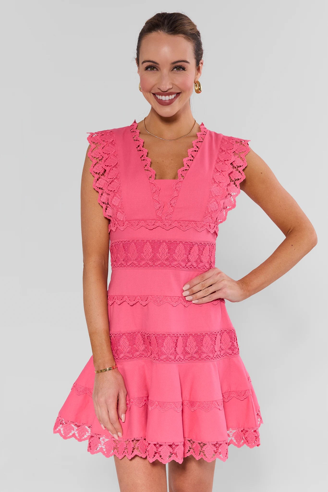 Woman wearing a pink dress with ruffled details on a white background