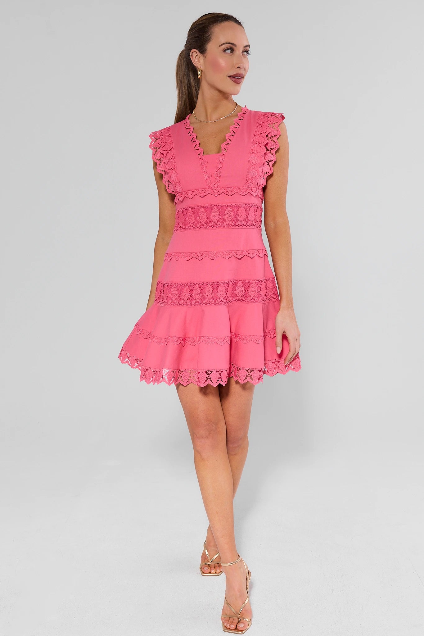 Woman wearing a pink dress with ruffled details on a white background