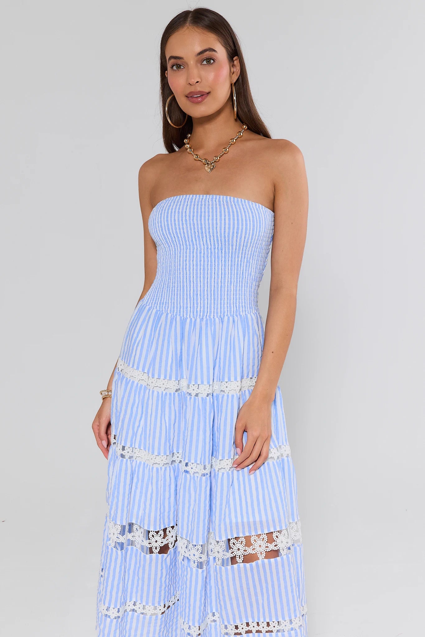 Woman wearing a light blue strapless dress with lace details on a gray background
