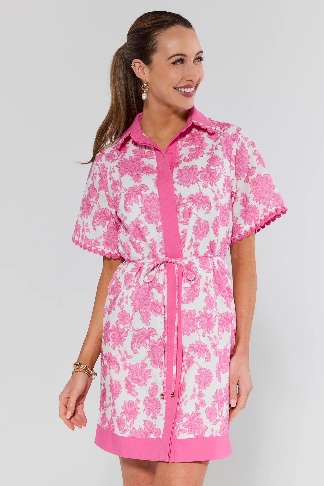 Woman wearing a pink and white floral dress against a plain background
