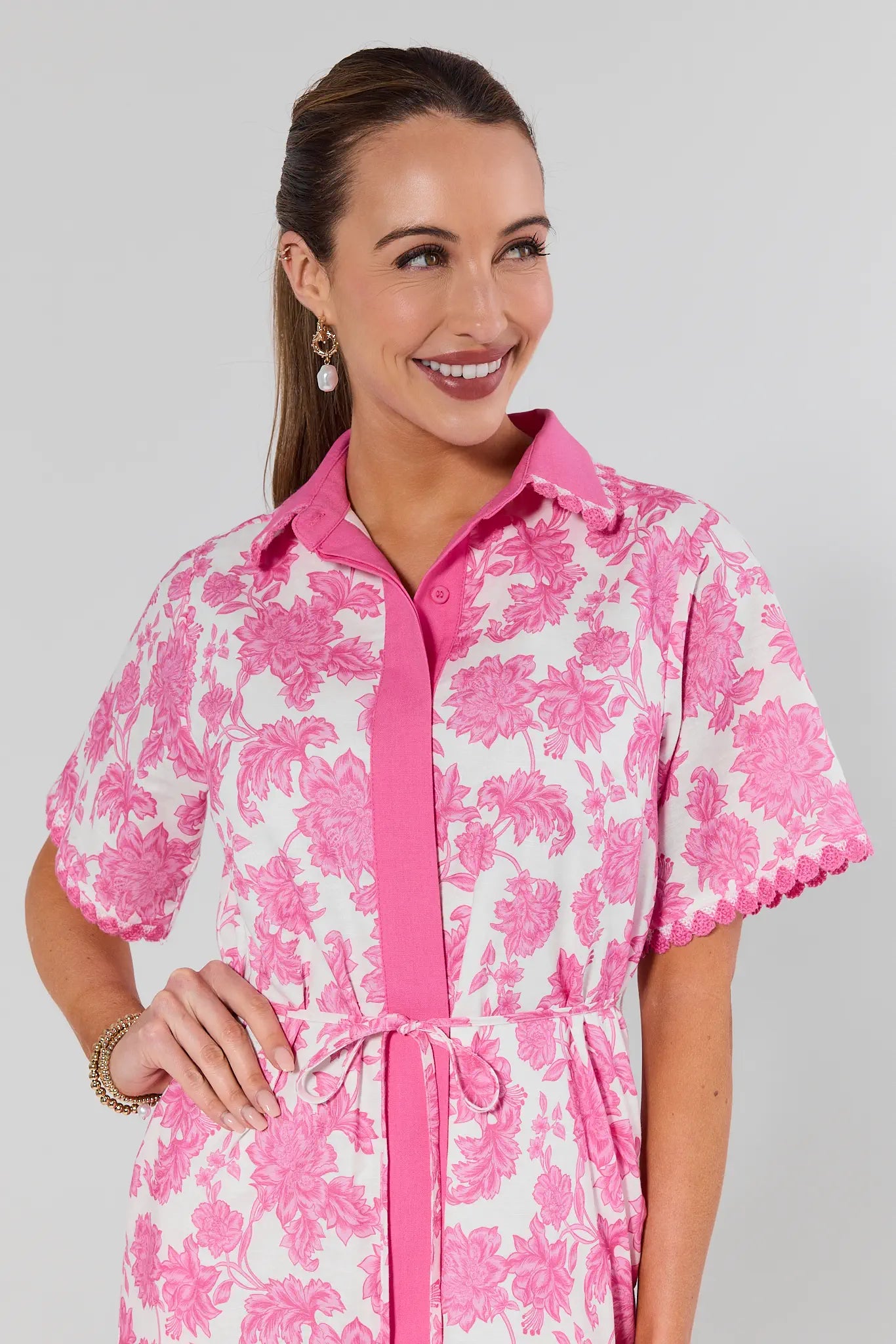 Woman wearing a pink and white floral dress against a gray background