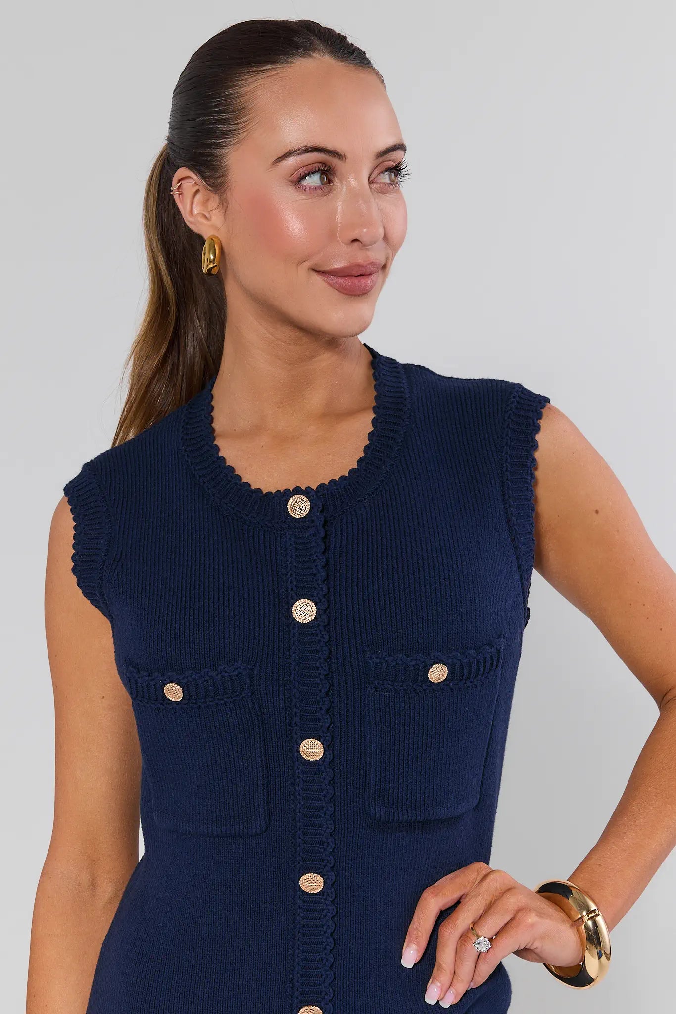 Woman wearing a navy blue sleeveless button-up dress against a plain background