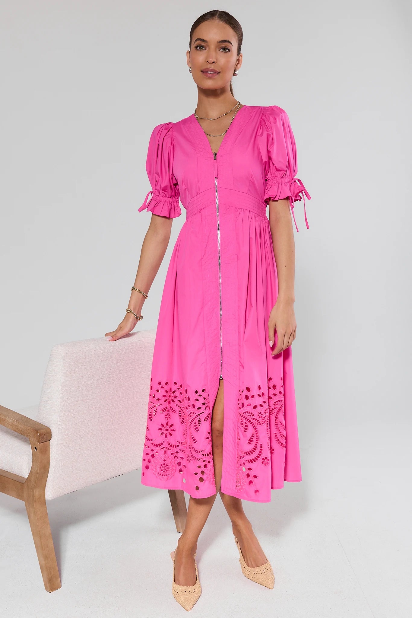 Woman wearing a bright pink dress with lace details on a white background