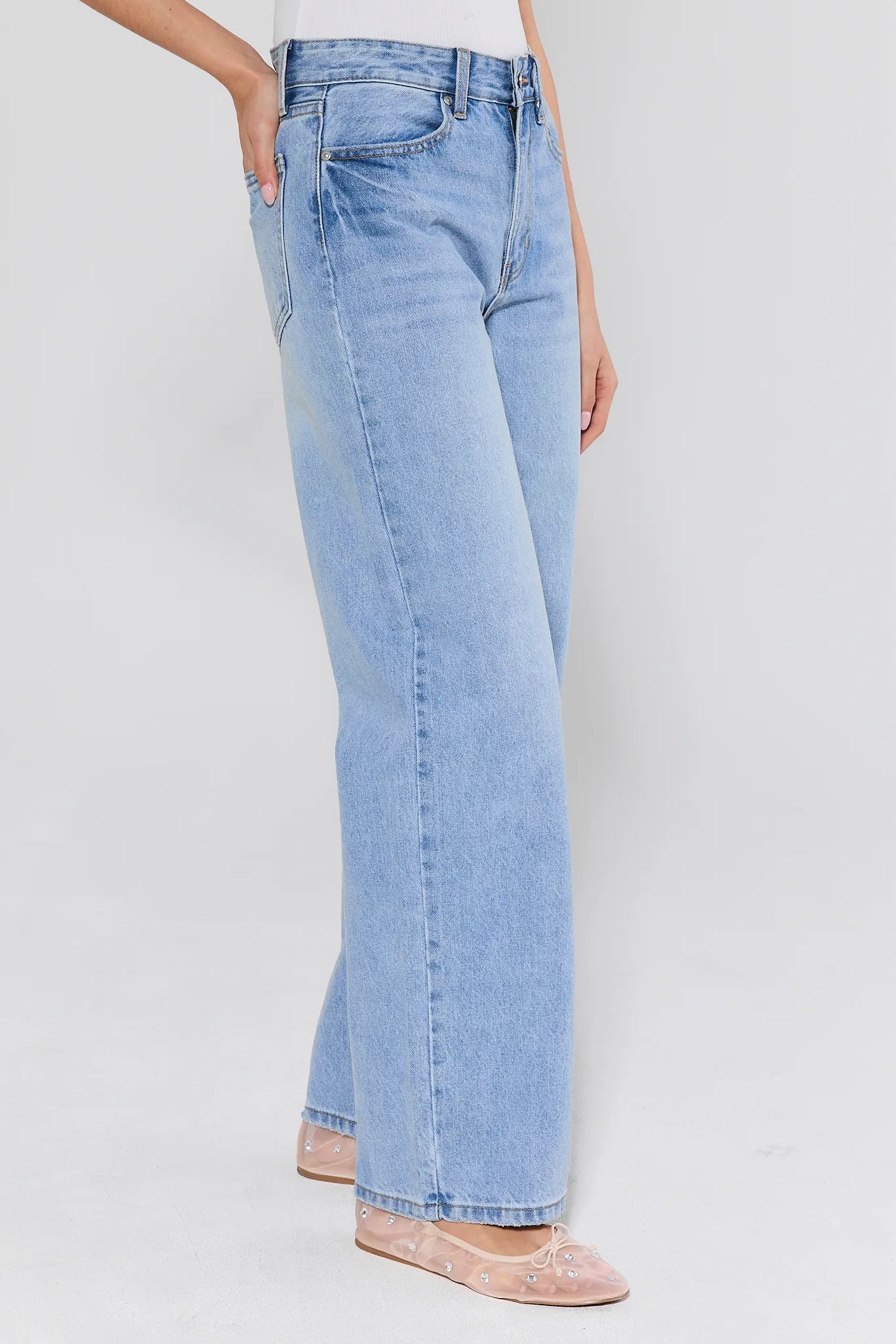 person wearing light wash jeans with mesh flats on white background