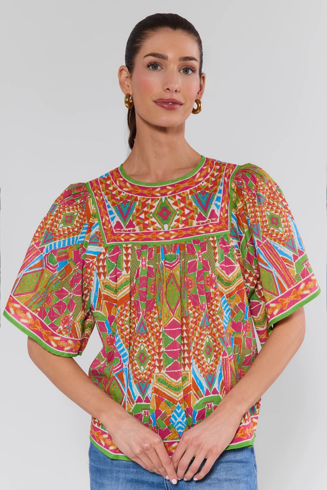 Woman wearing a colorful patterned blouse against a white background