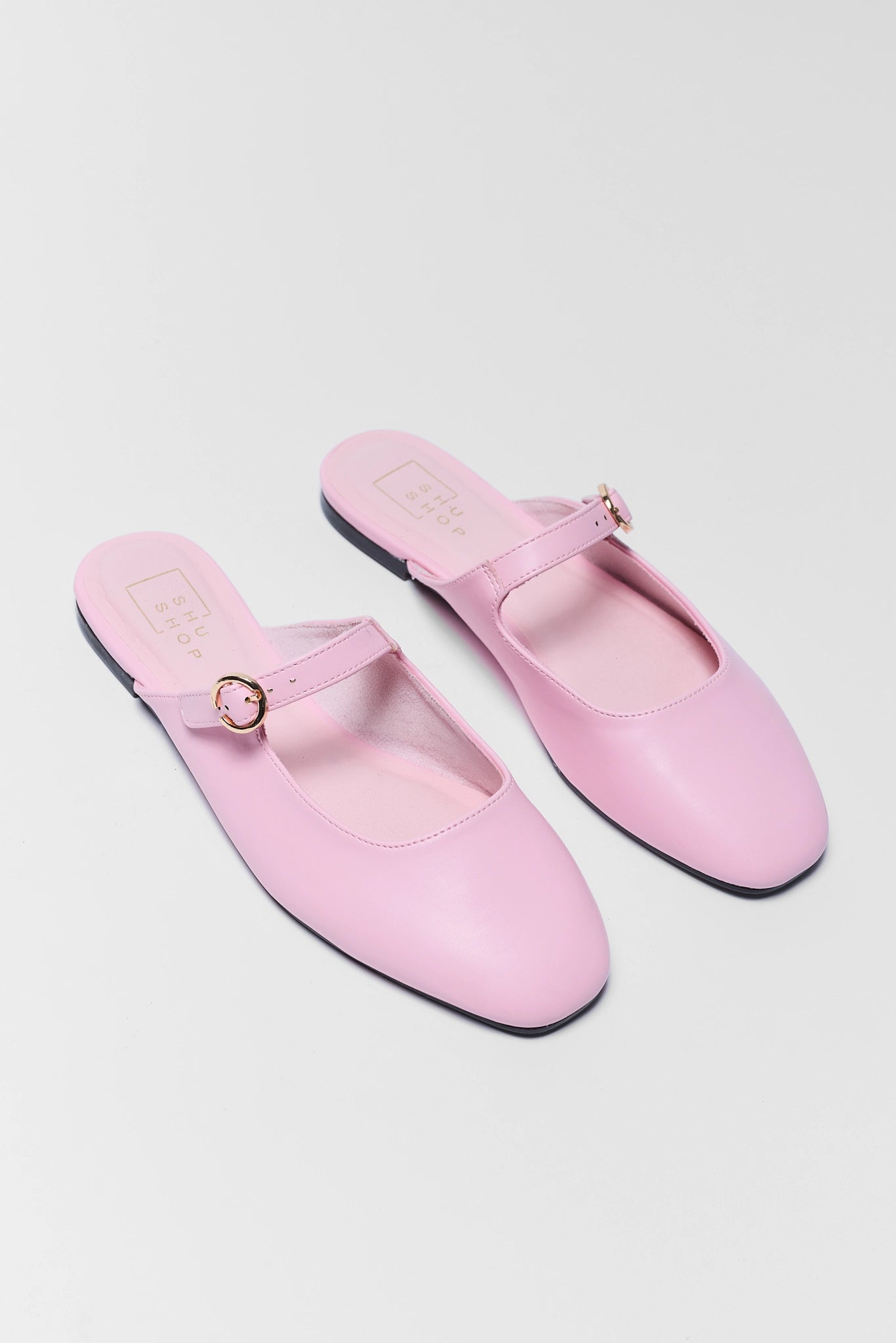 Pair of pink shoes with buckles on a light gray background