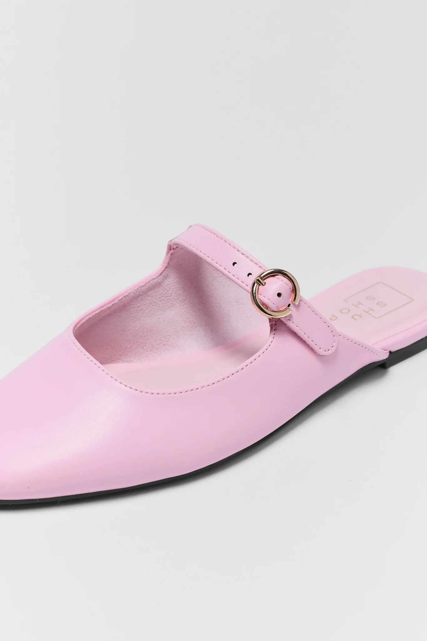 Pink flat shoe with a strap on a light background