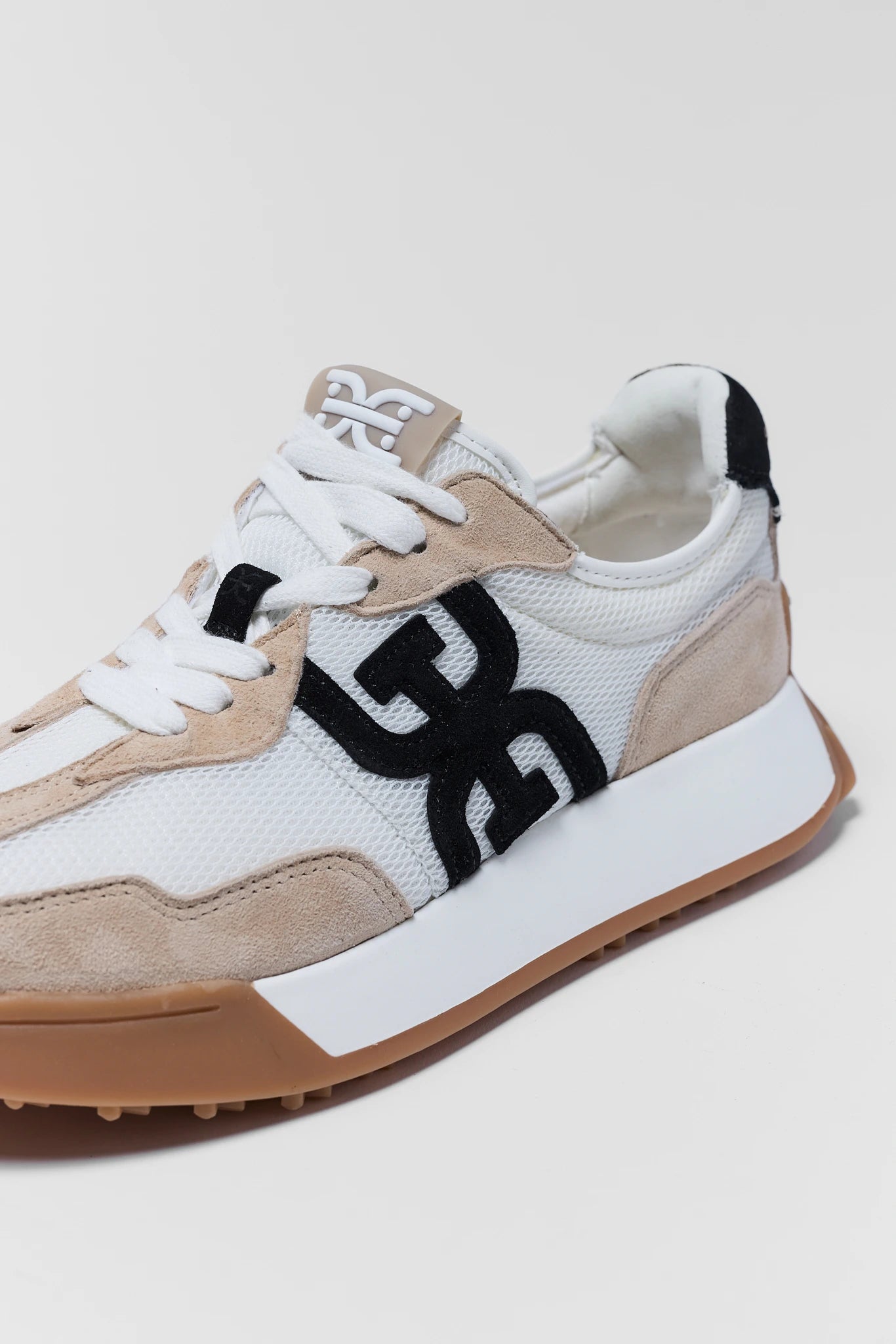 Sneaker with a prominent black logo on a light background